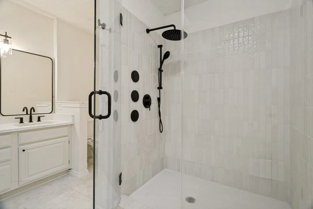 Bathroom featuring a textured ceiling, tile patterned flooring, vanity, and a shower with door

