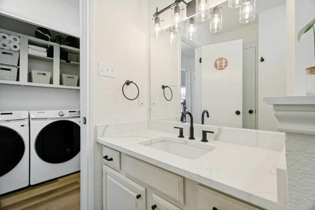 Laundry area with washer hookup, hardwood / wood-style flooring, and electric dryer hookup. Across from the guest bathroom