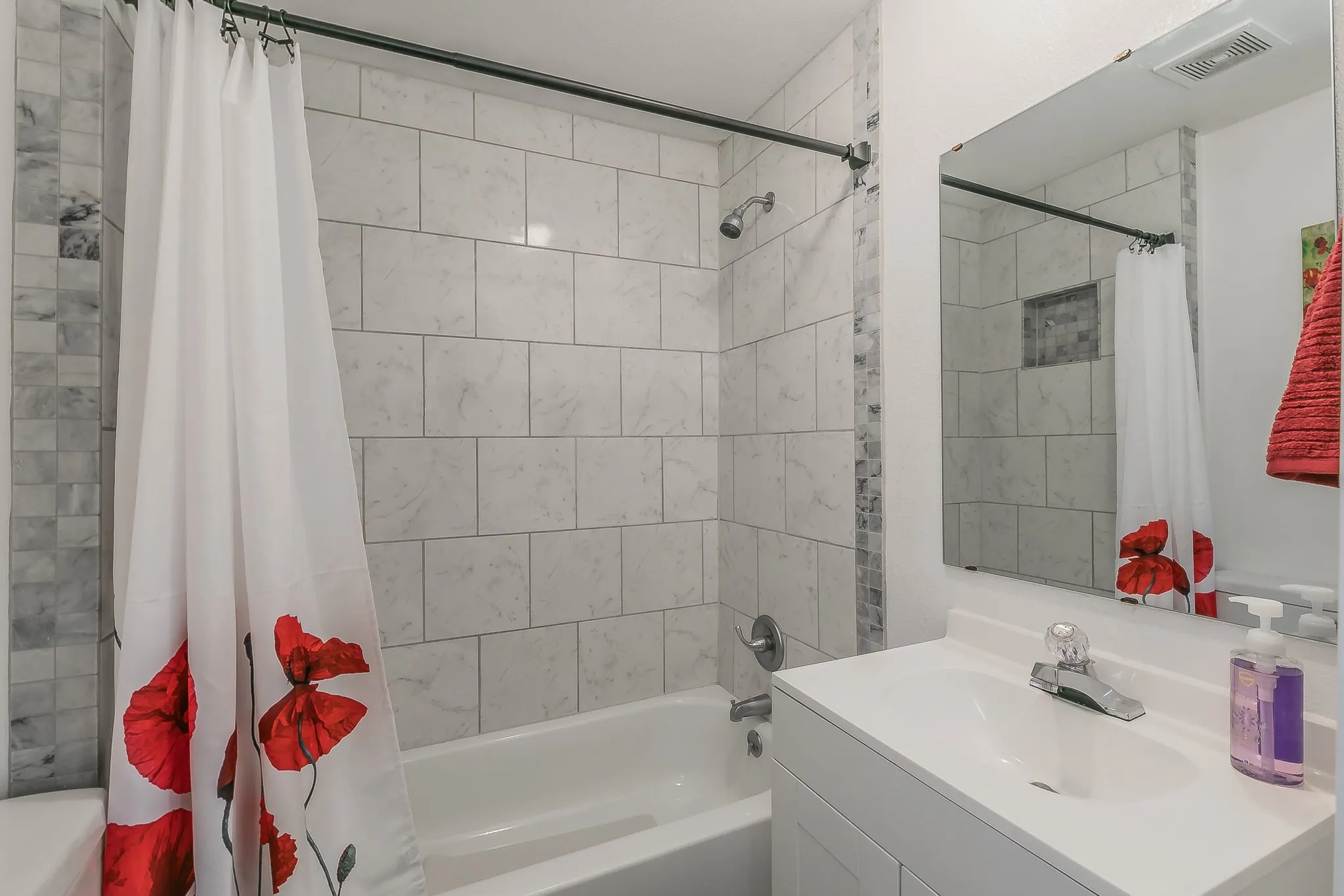 White subway tile surrounding the tub, featuring a built-in shower niche