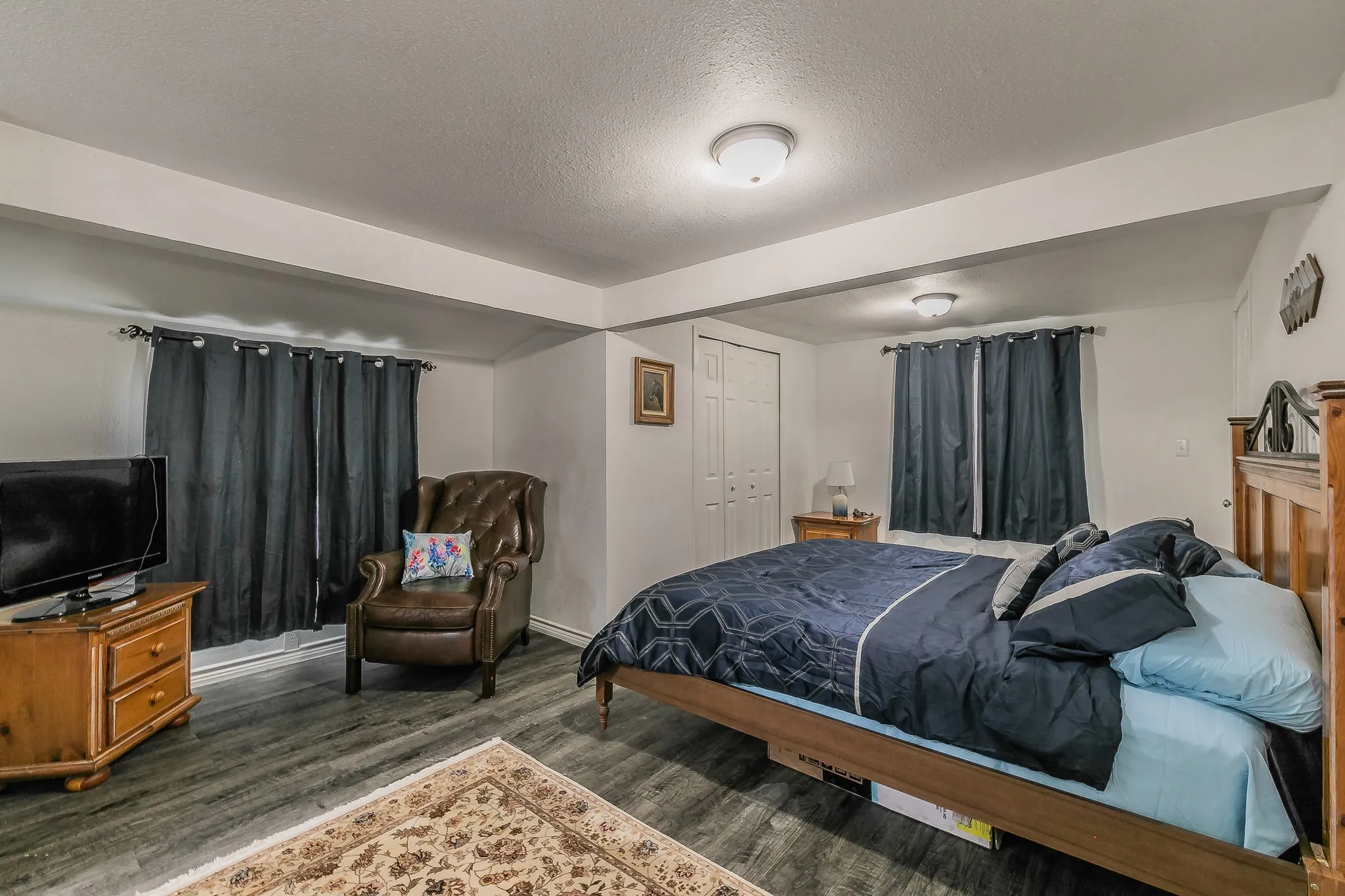 Spacious room featuring wood-finish flooring, white walls, and recessed lighting