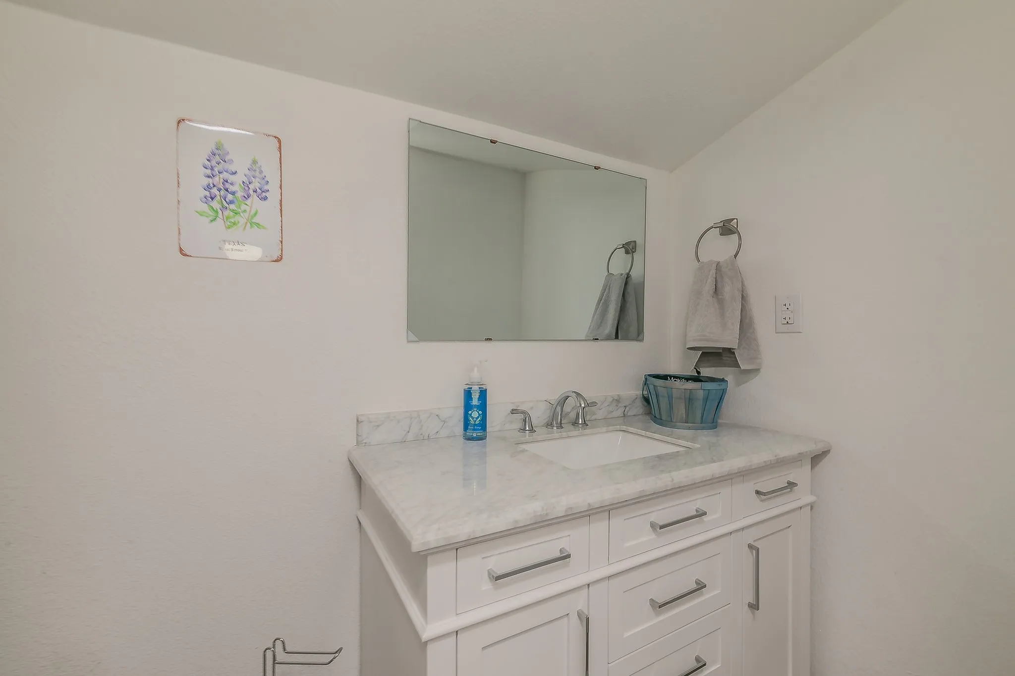 White vanity with an integrated sink, polished chrome faucet, and a stone-finish countertop