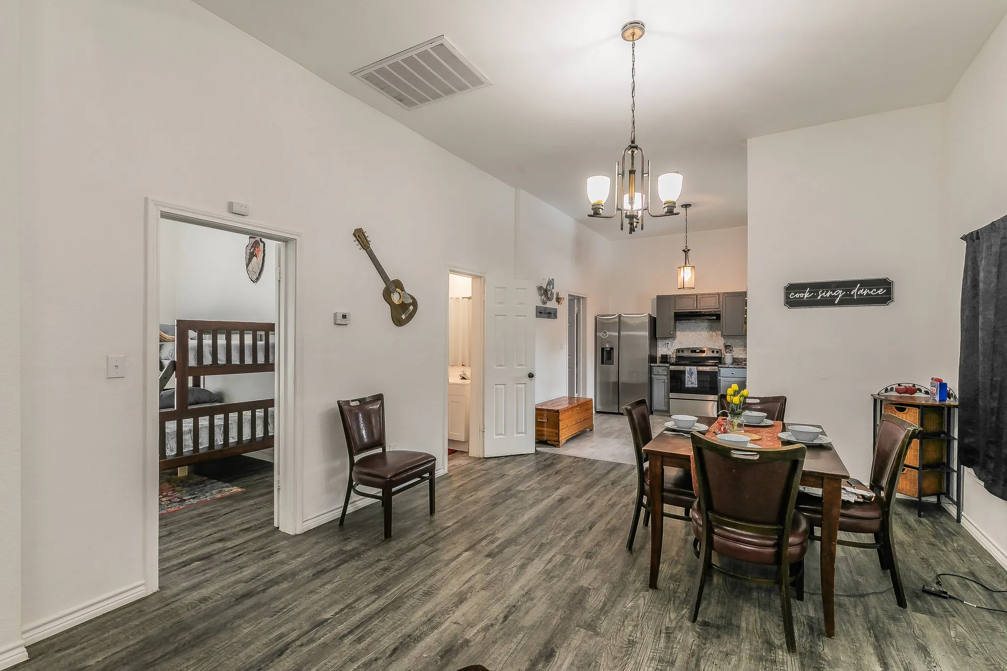 Open-concept living space featuring wood-finish flooring, recessed lighting, and a modern chandelier