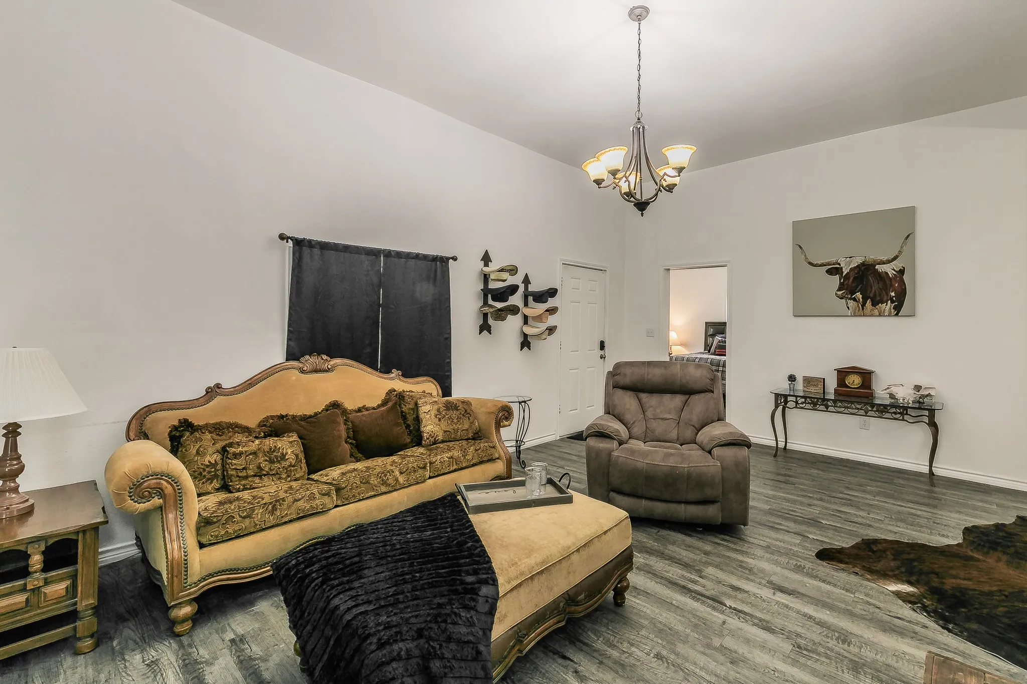 Vaulted ceiling with an attached chandelier, wood-finish flooring, and white walls