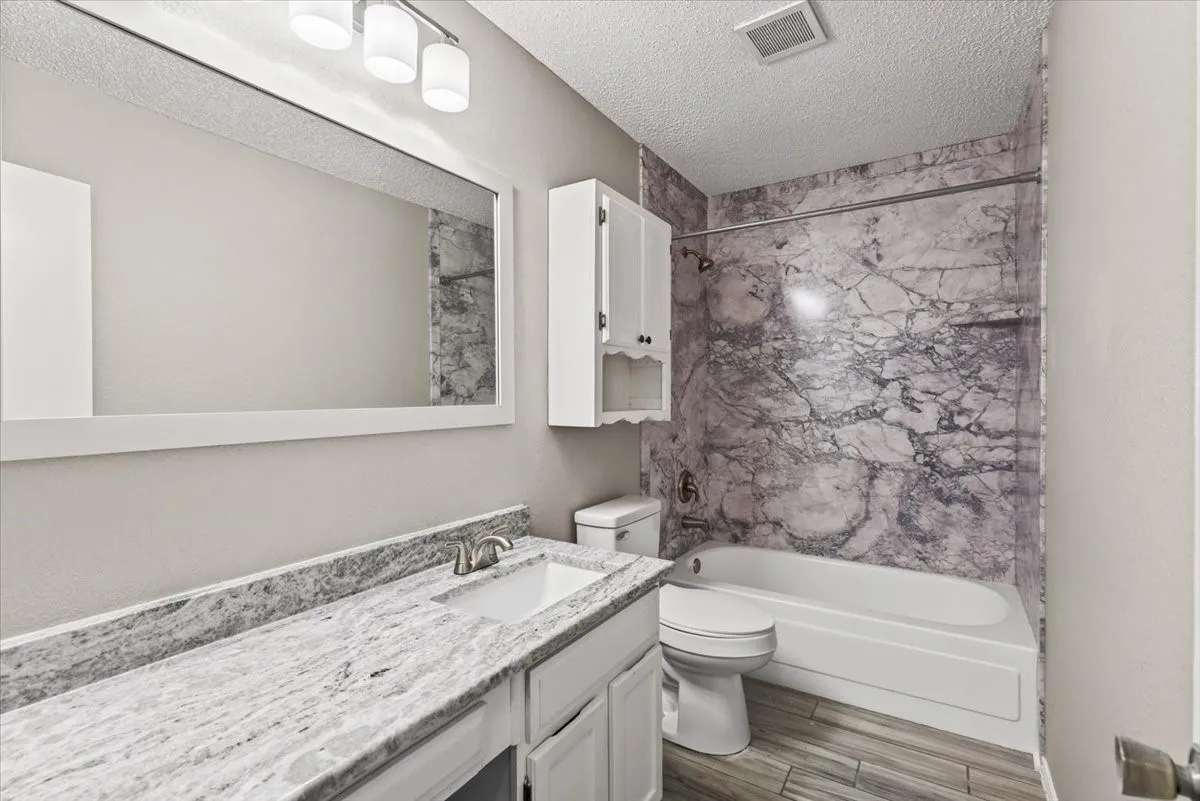 Secondary bathroom with granite countertops and updated shower surround.