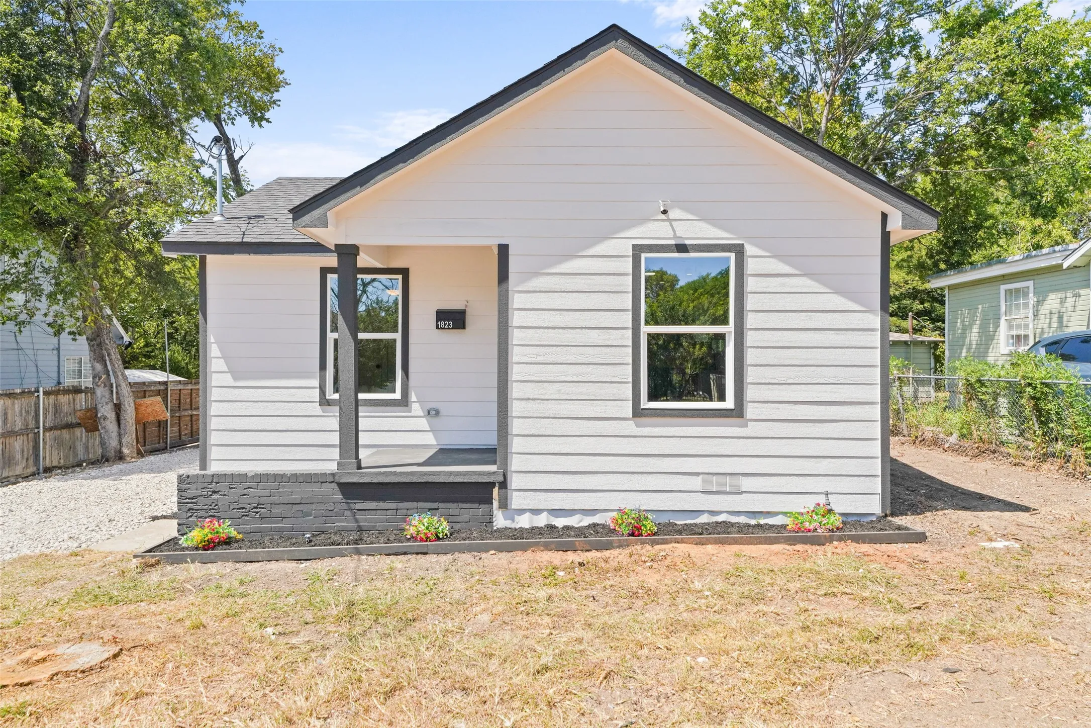 White horizontal siding with dark trim, covered porch entry, and a dark shingle roof