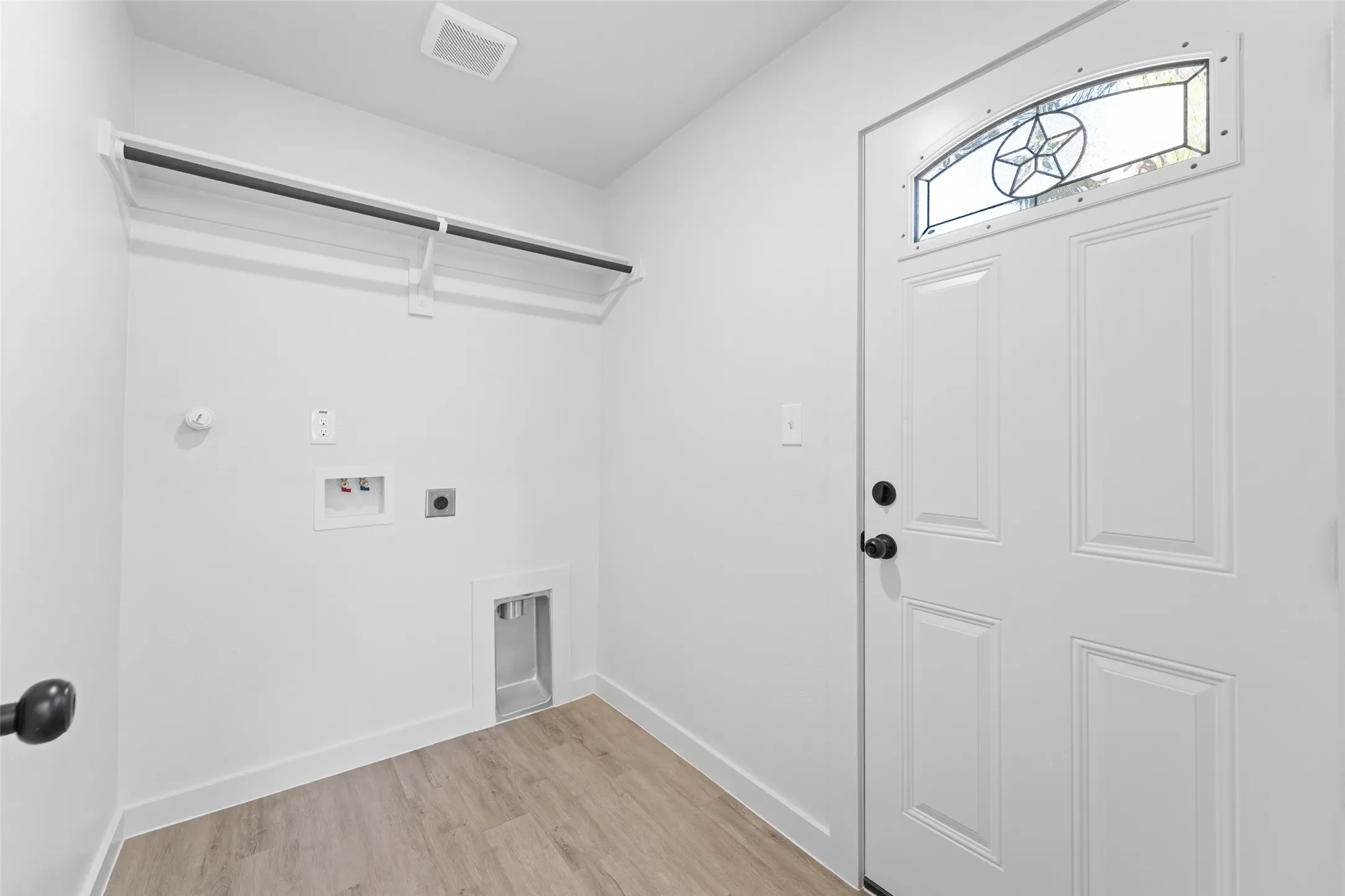 Laundry area featuring wood-finish flooring, washer/dryer hookups, and a built-in hanging rack