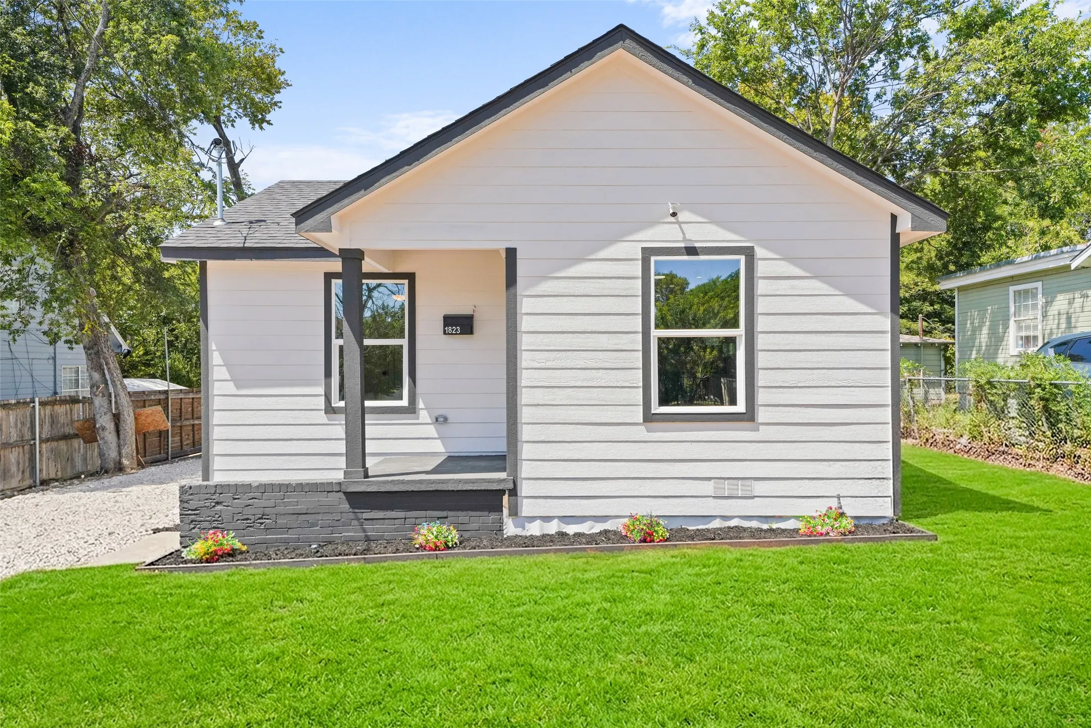Gable roof architecture with horizontal siding, dark trim windows, covered porch, and ai generated lawn