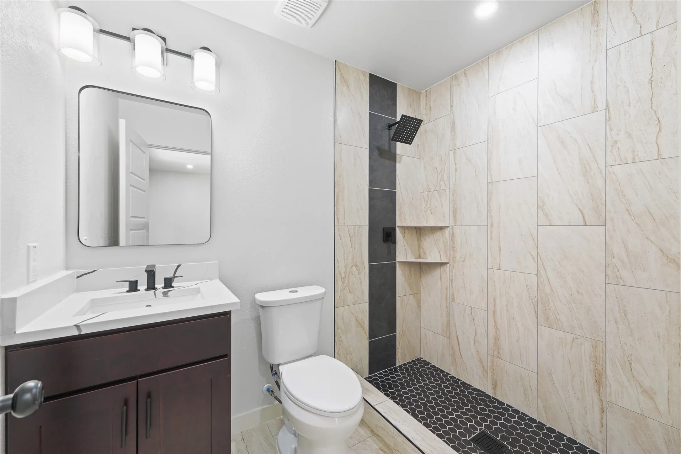 Modern vanity with a rectangular basin, matte black faucet, and contemporary lighting fixture