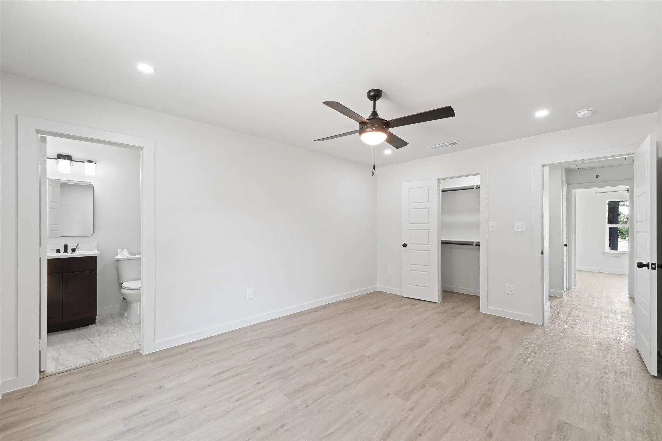 Recessed lighting, wood-finish flooring, ceiling fan, and white doors with dark hardware