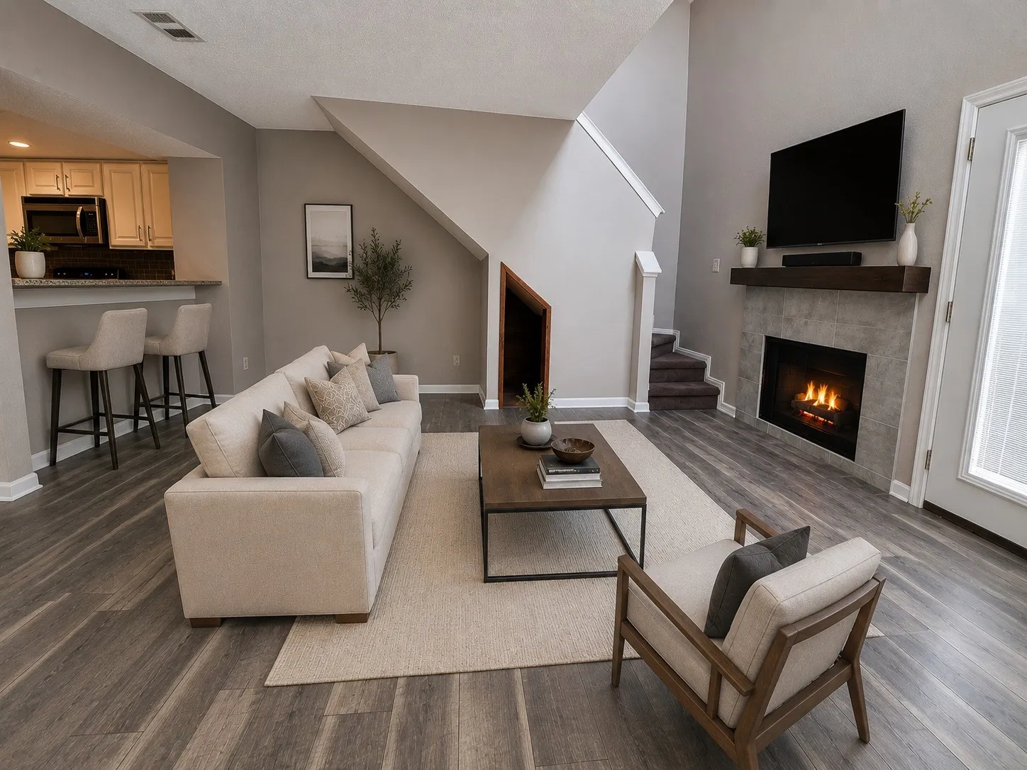 Open concept living space featuring a two-story ceiling, wood-finish flooring, and a fireplace with a wood mantel virtually staged