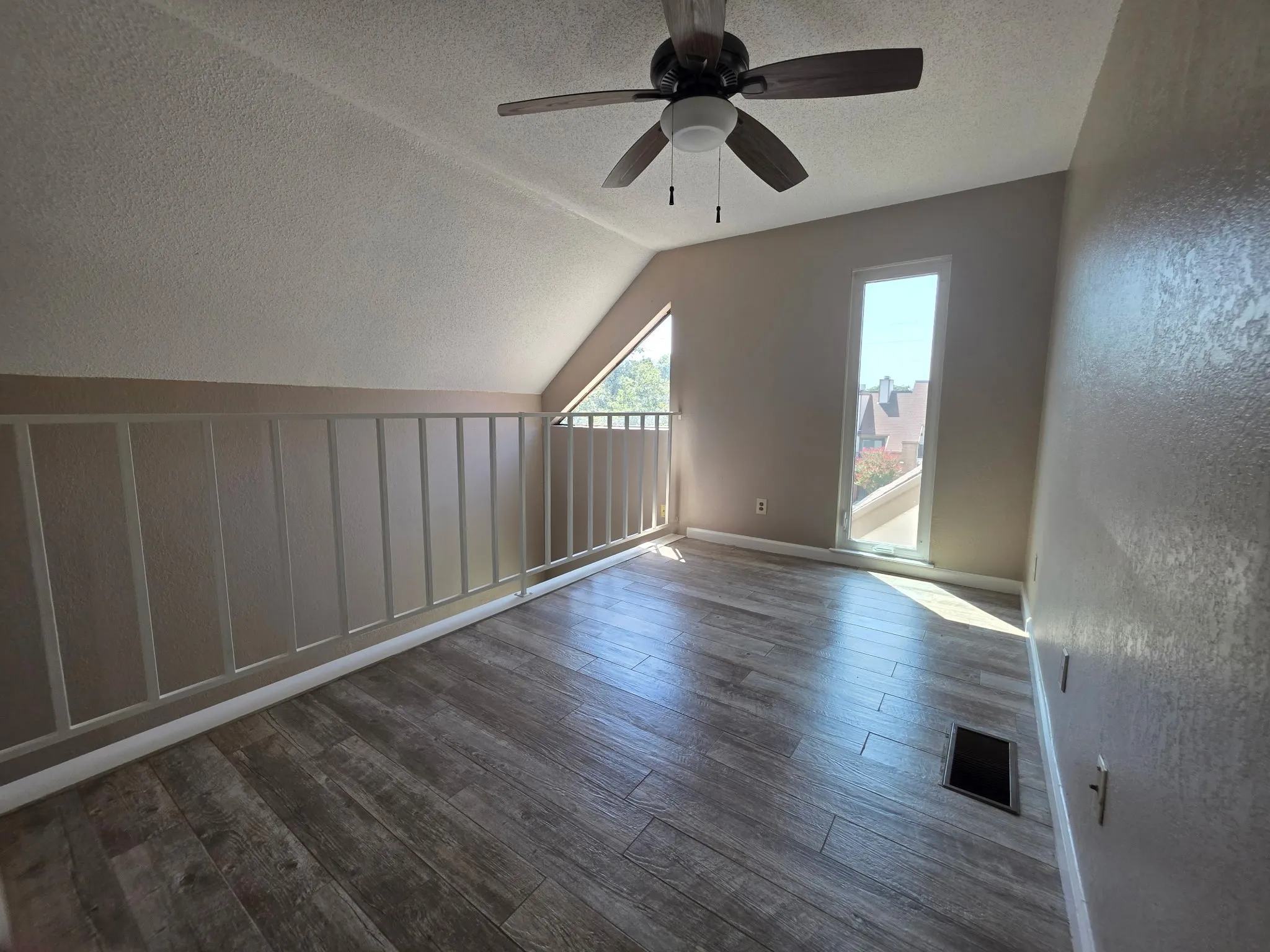Wood-finish flooring, vaulted ceiling, ceiling fan, and prominent windows with natural light