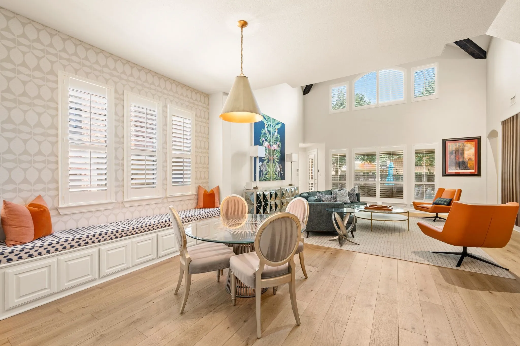 Vaulted ceiling with exposed beams, wood-finish flooring, built-in window seating with storage, plantation shutters, and a prominent pendant light fixture