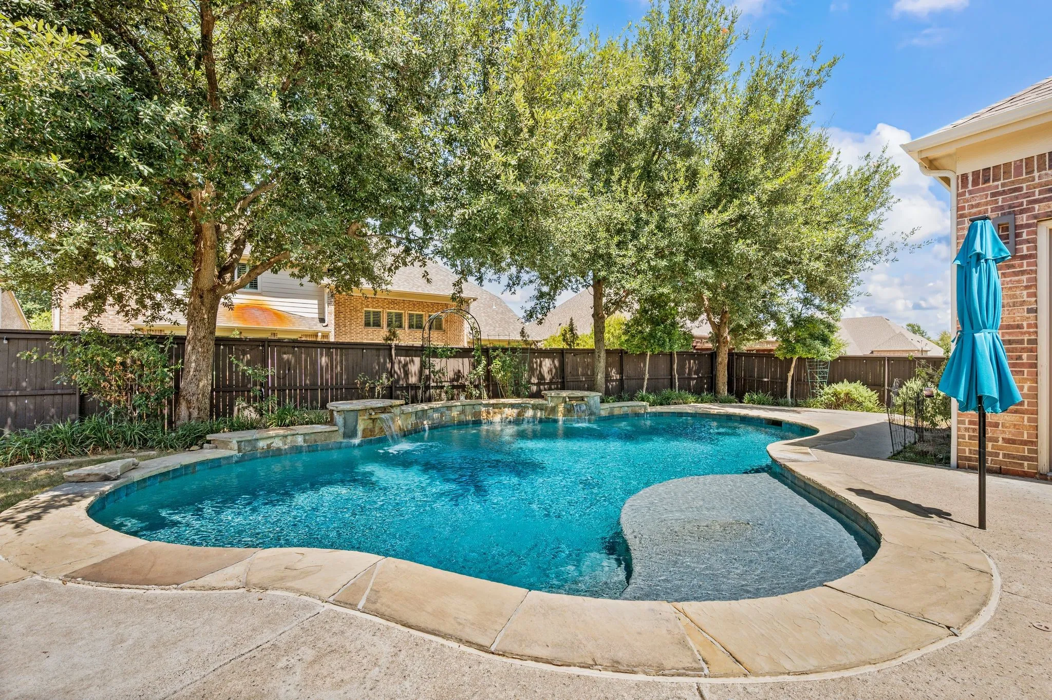 Freeform swimming pool with stone coping, and waterfall feature