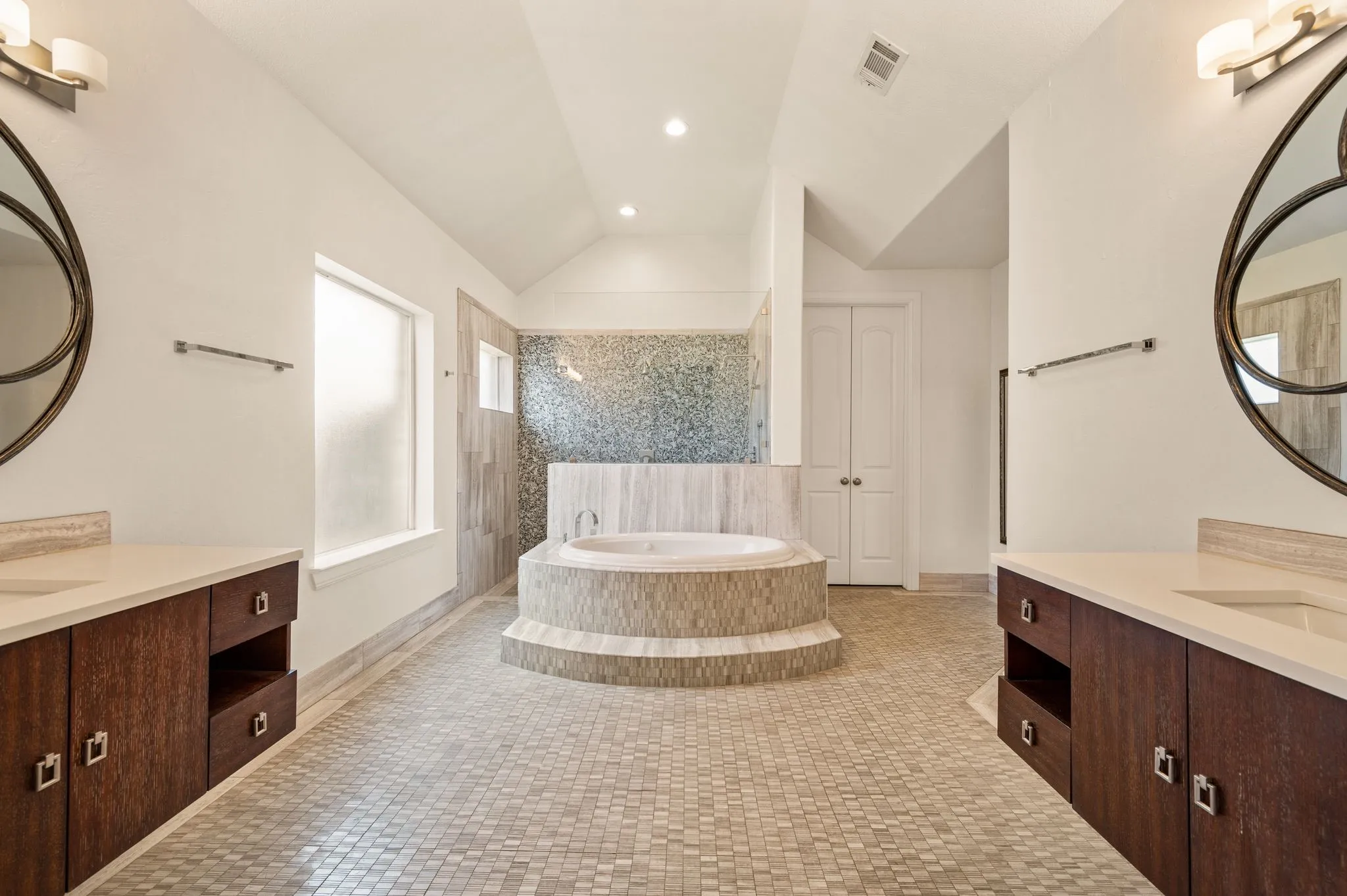 Dual vanity with warm wood-finish cabinetry, light countertops, and integrated sinks