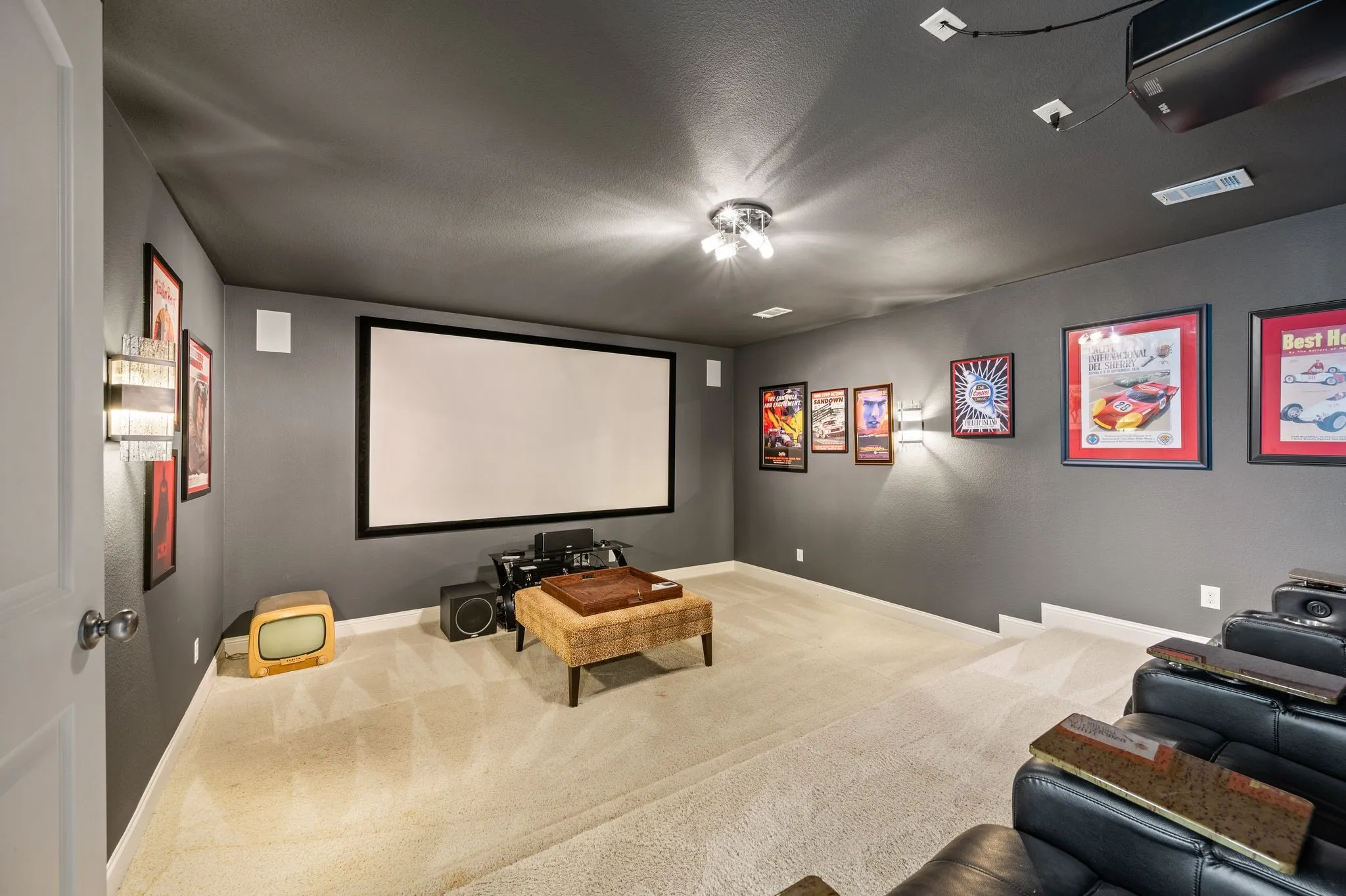 Dedicated media room featuring a large projection screen, integrated ceiling projector, wall-mounted speakers, and recessed lighting
