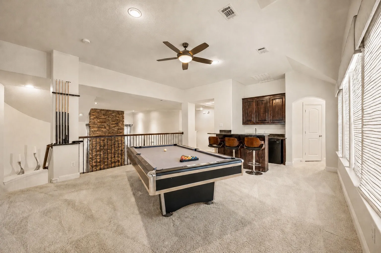 Spacious upstairs area featuring a built-in wet bar with dark wood cabinetry, a ceiling fan, and recessed lighting
