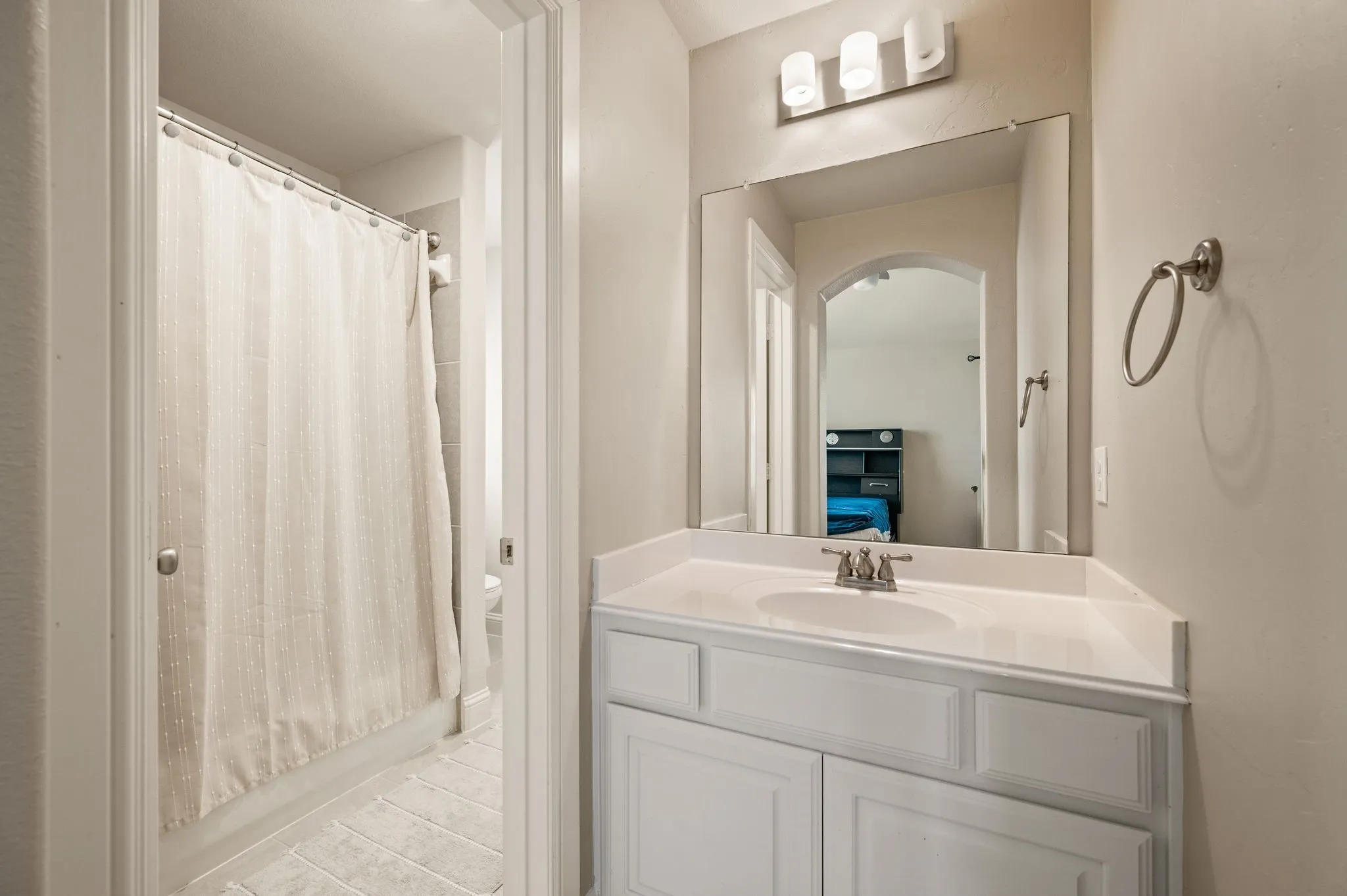 Jack and Jill bathroom. White vanity with a single basin sink, brushed nickel faucet, and a large wall-mounted mirror