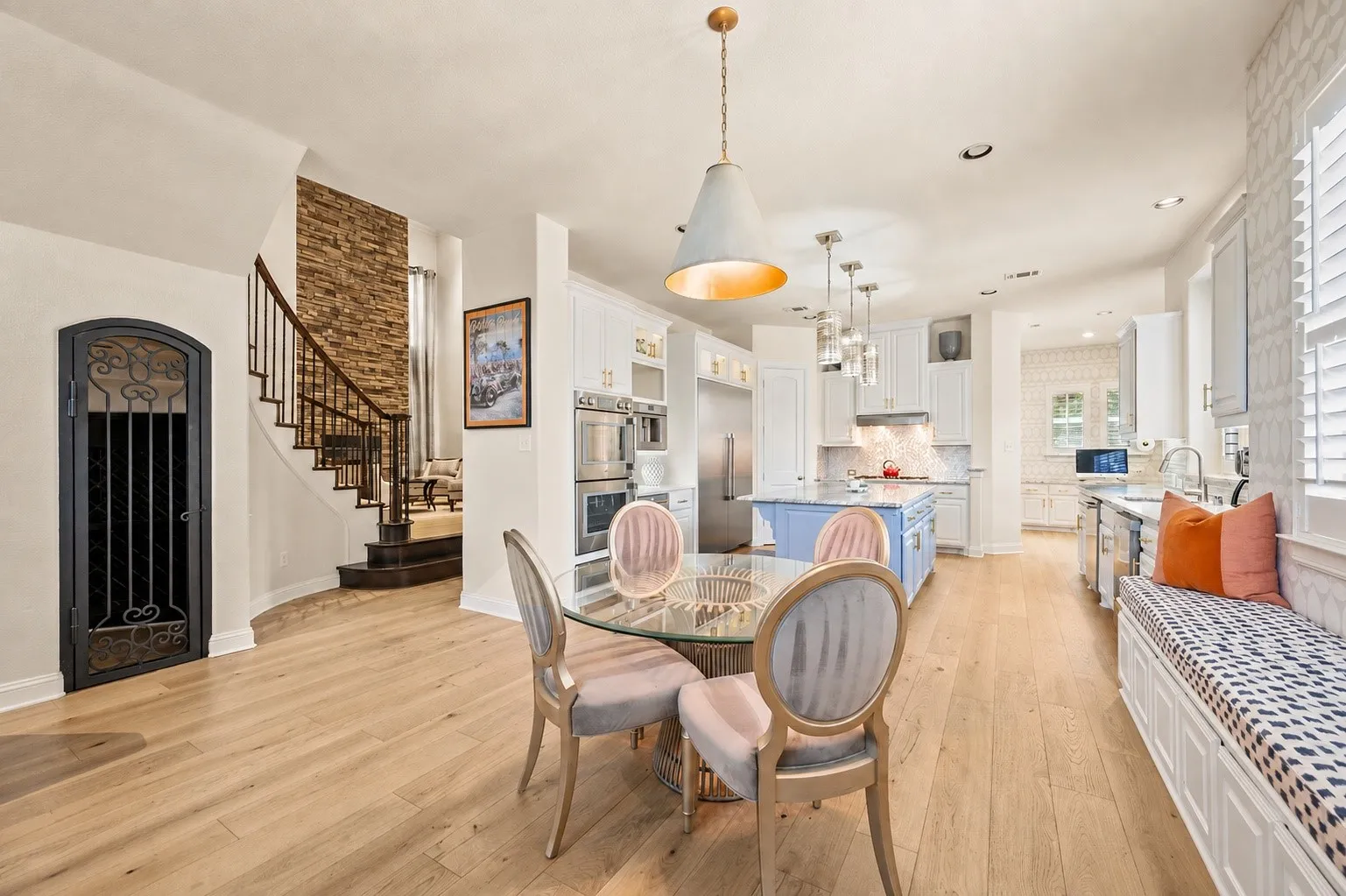 Gourmet kitchen with double ovens and a central island, light wood flooring, built-in window seating, and a decorative wrought iron door