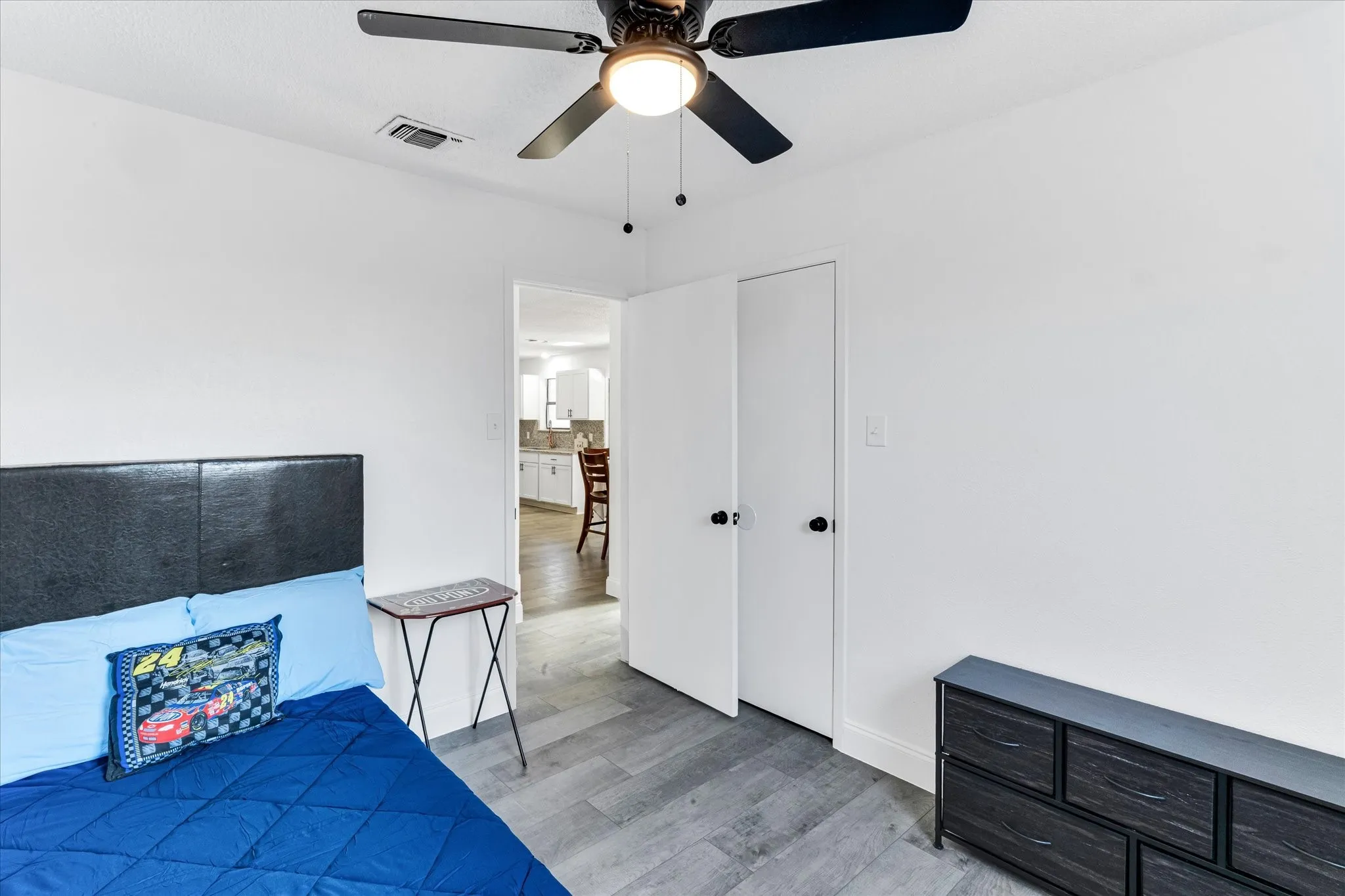 Interior room featuring wood-finish flooring, white walls, and a ceiling fan with integrated lighting