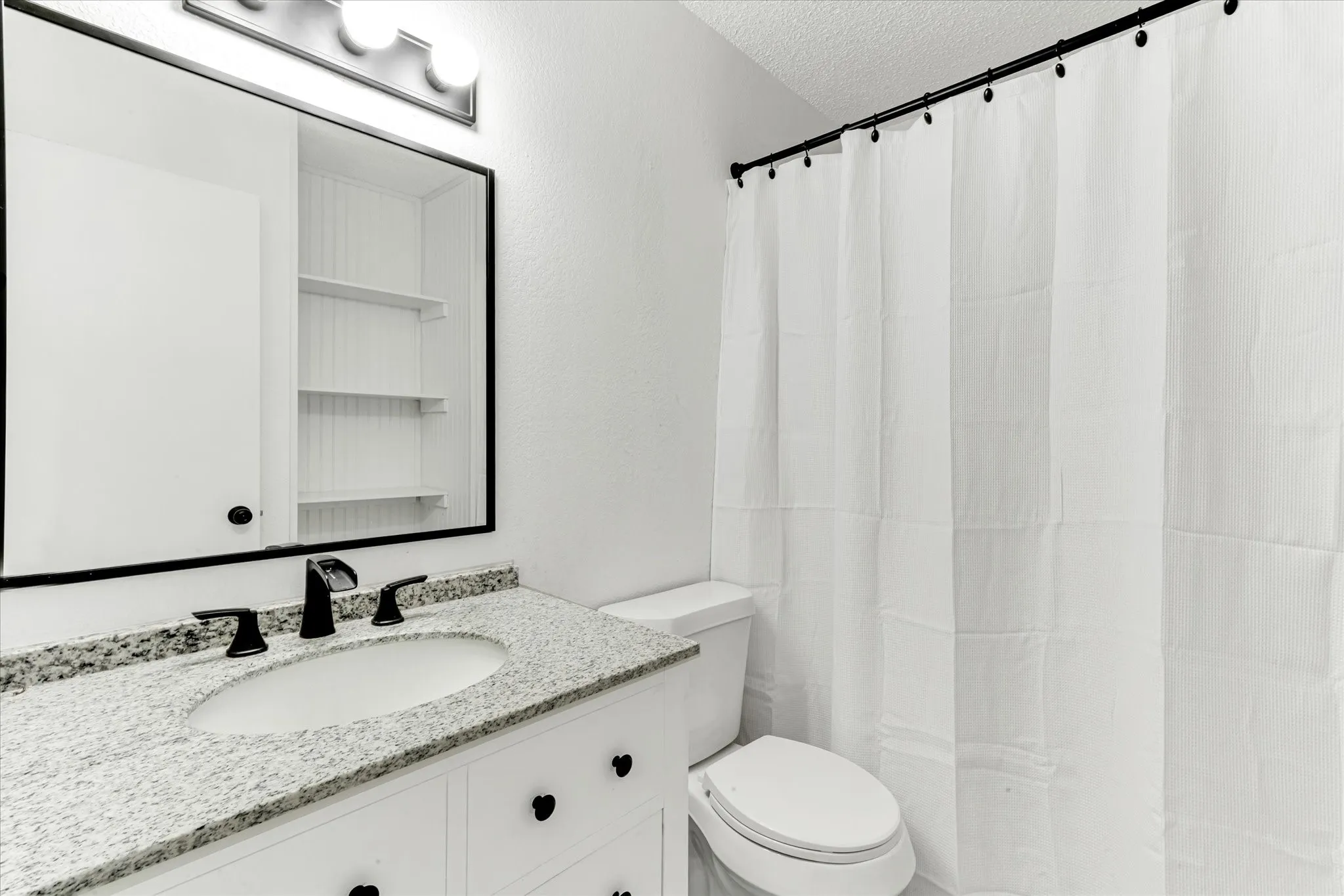 Vanity with a granite-style countertop, undermount sink, and matte black faucet