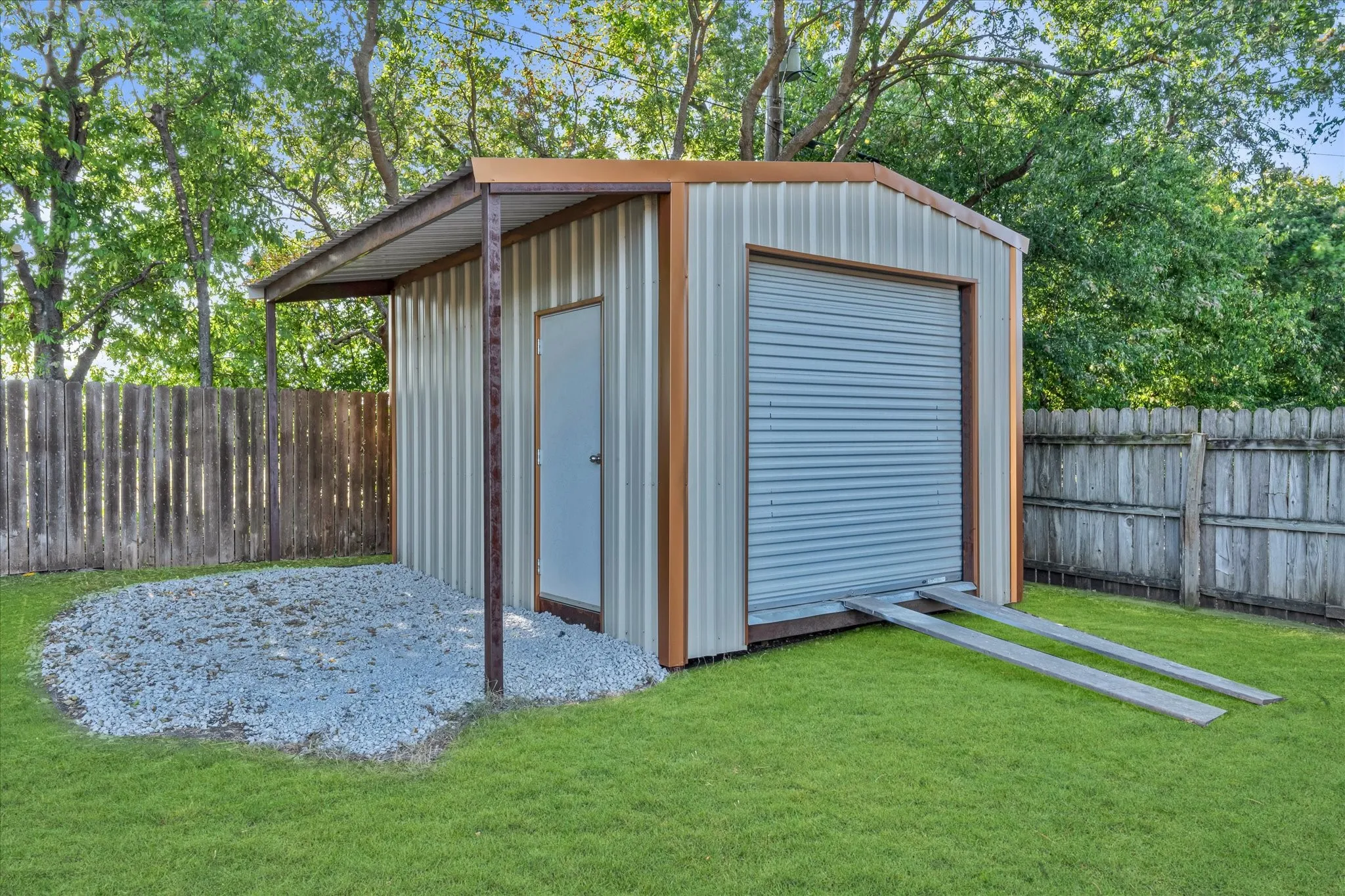Metal utility building featuring a roll-up door, side entry door, and an attached awning