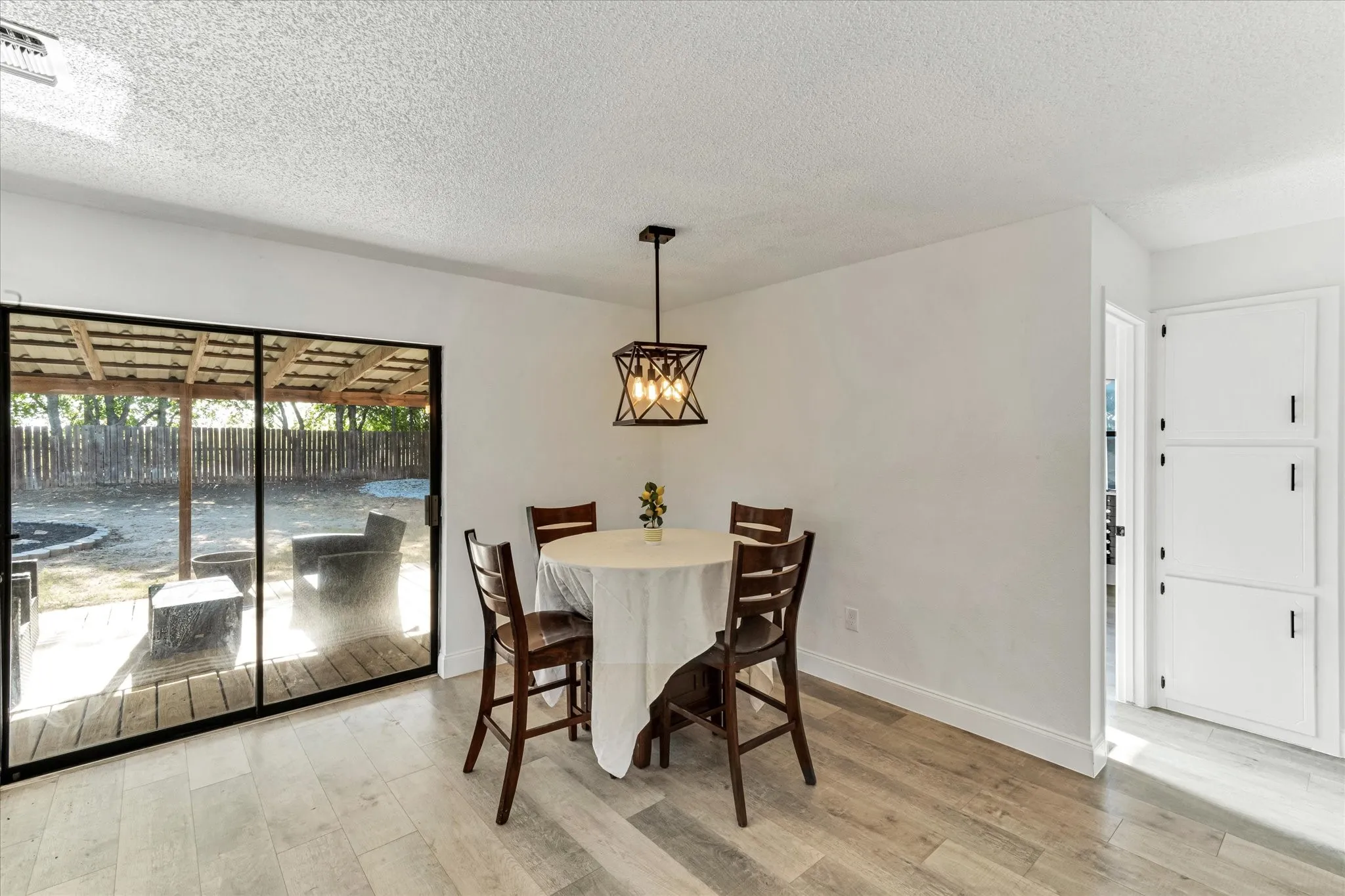 Wood-finish flooring, sliding glass door, overhead decorative light fixture, built-in storage cabinets, and a covered patio area