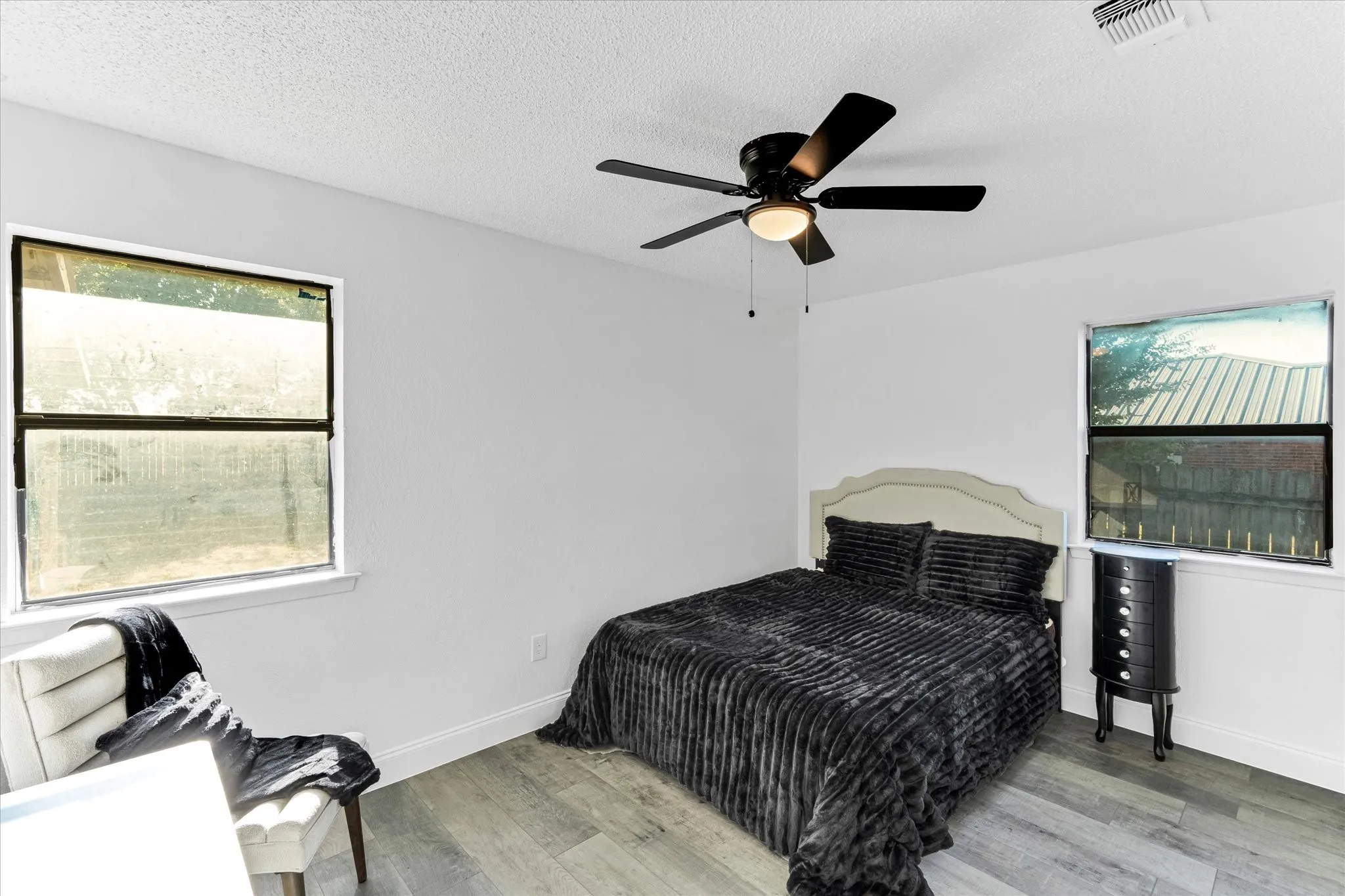 Wood-finish flooring throughout, bright white walls, and a ceiling fan with integrated lighting