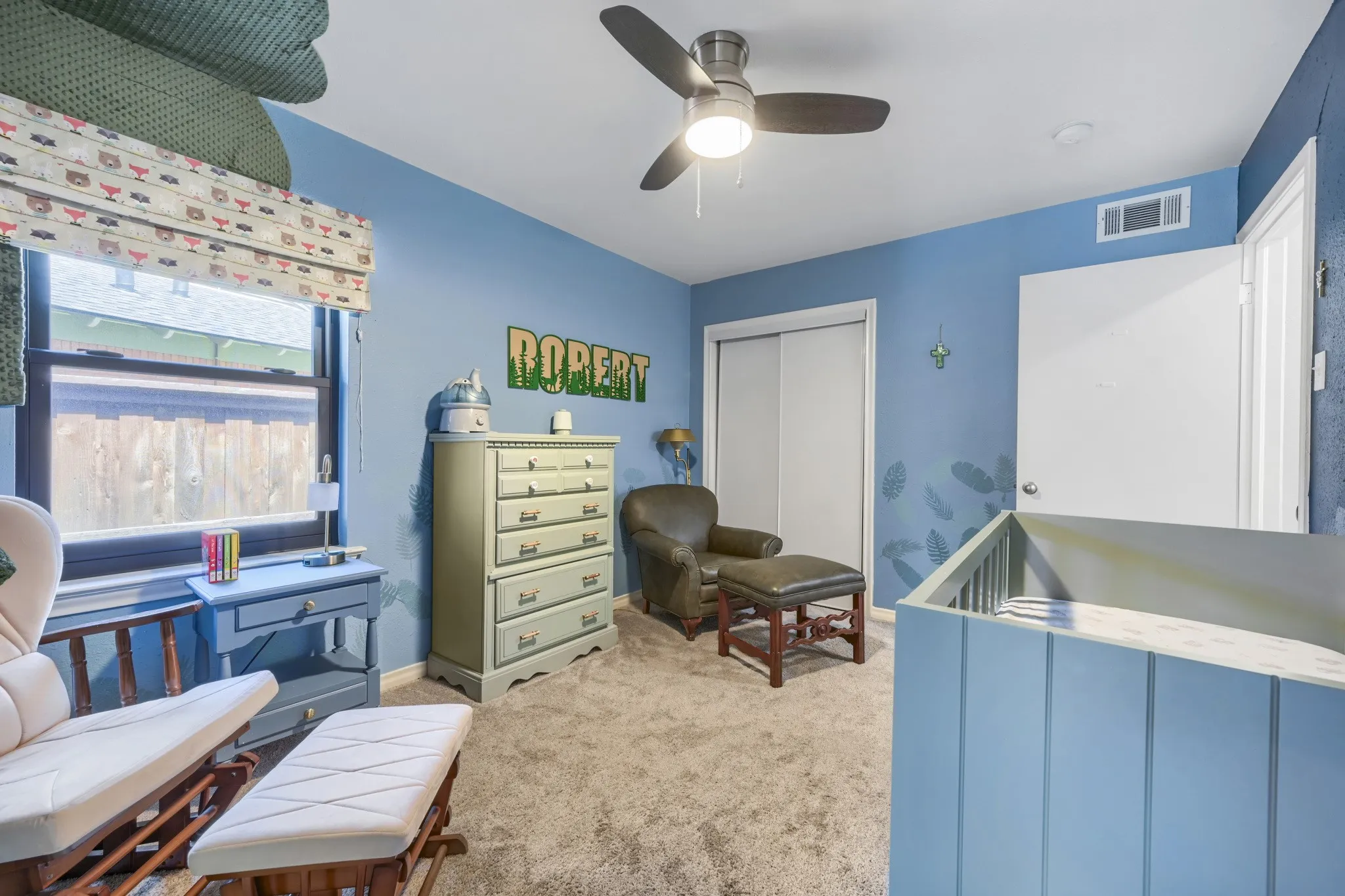 Room featuring carpet flooring, ceiling fan with integrated lighting, window with roller shade, and sliding closet doors