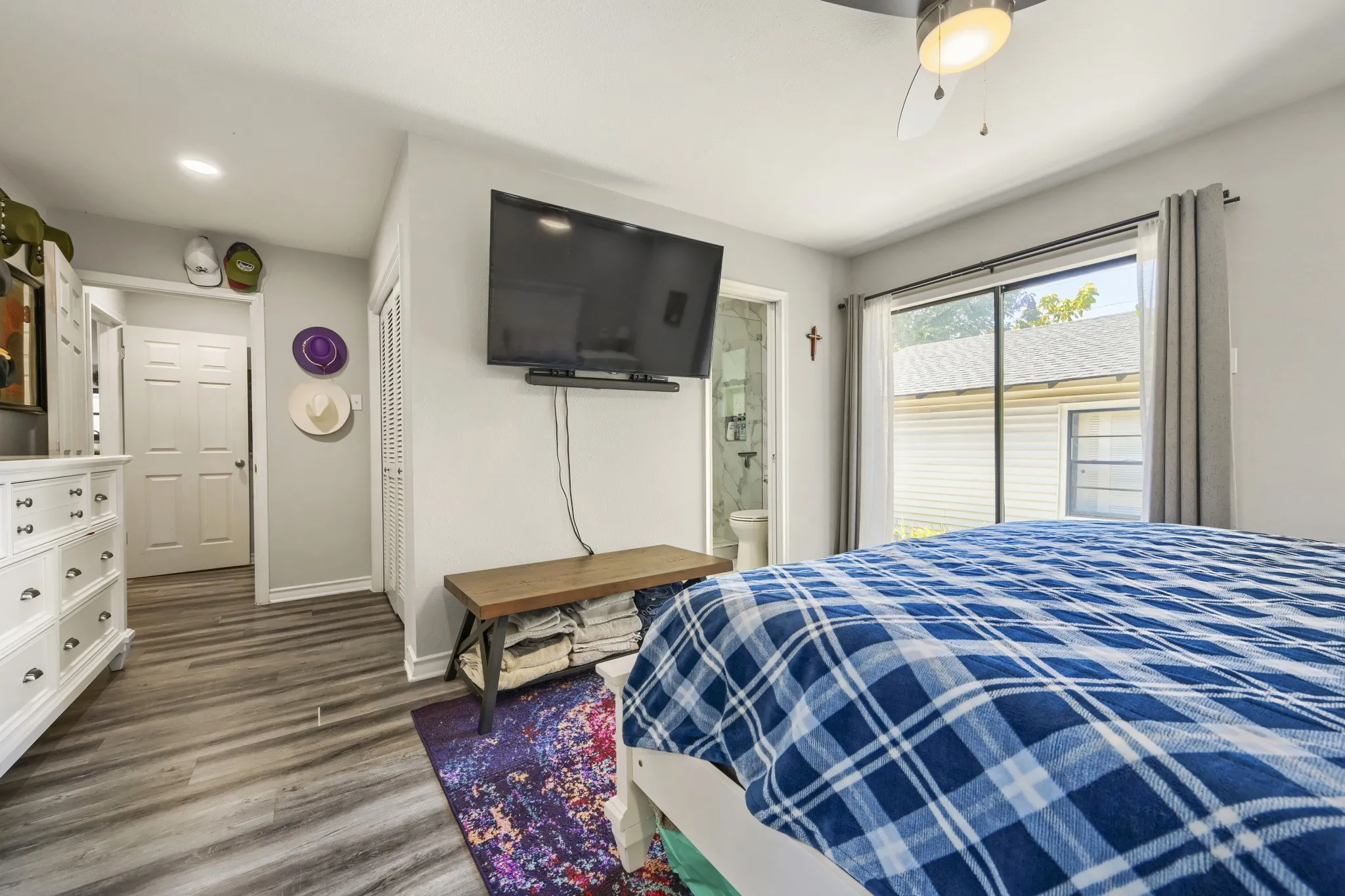 Wood-finish flooring, ceiling fan with integrated lighting, and a sliding glass door providing natural illumination