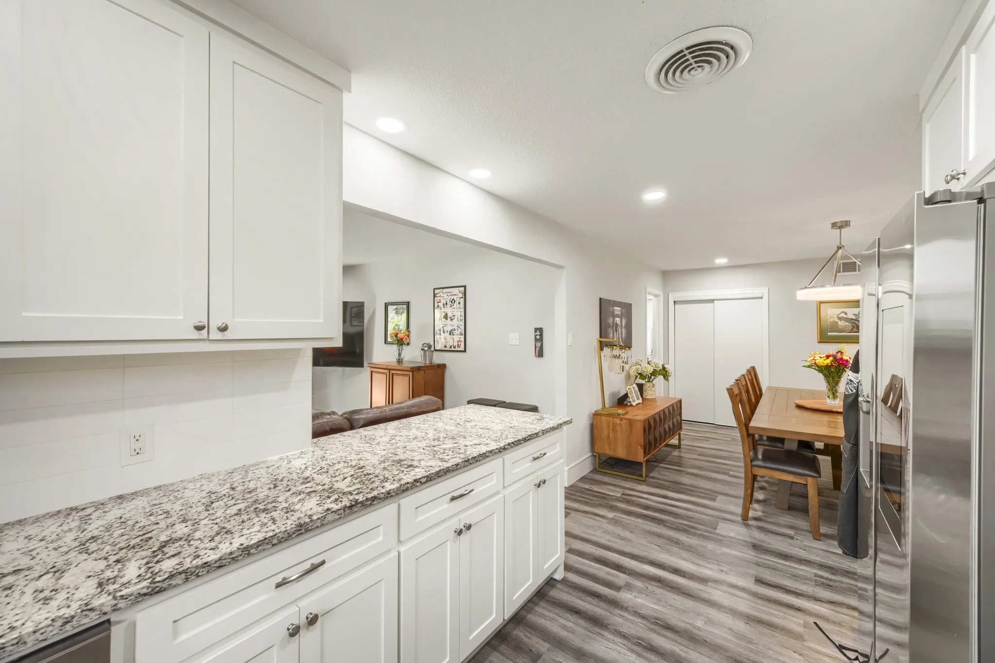 Kitchen featuring granite countertops, white shaker cabinetry, and a white subway tile backsplash