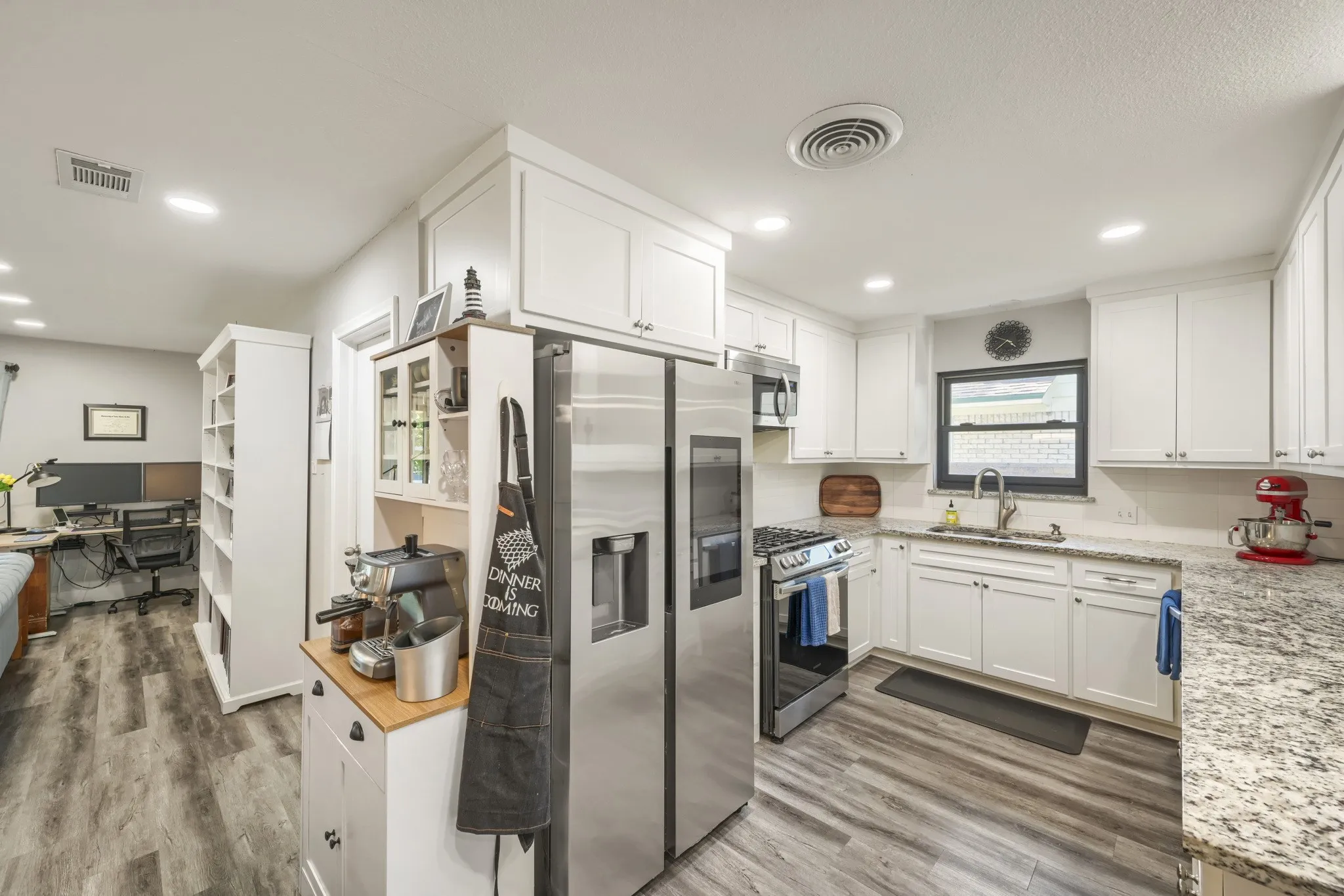 Kitchen featuring white cabinetry, stainless steel appliances, speckled stone countertops, and wood-finish flooring