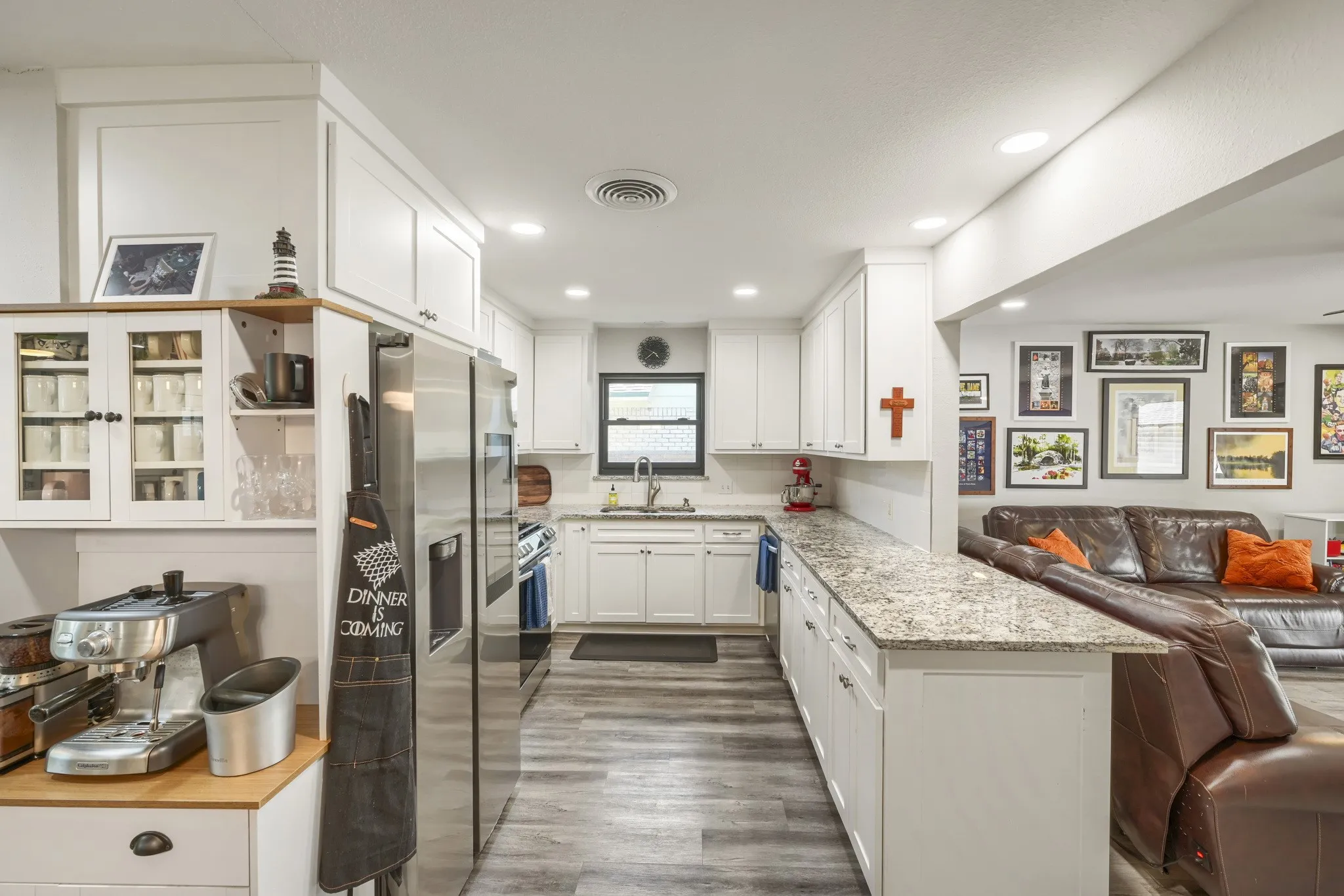 White cabinetry with modern hardware, stone countertops, stainless steel appliances, wood-finish flooring, and recessed lighting