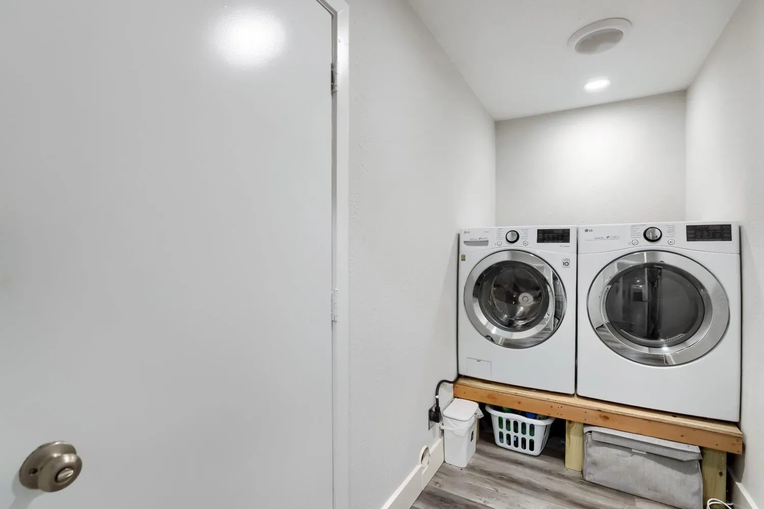 White front-loading washer and dryer set, recessed ceiling lighting, wood-finish flooring
