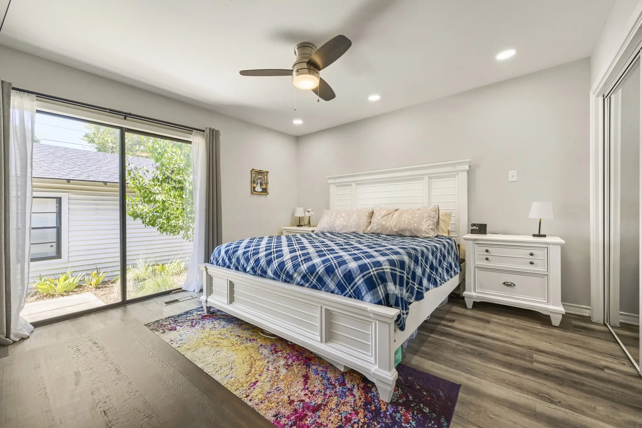Sliding glass door, wood-finish flooring, recessed lighting, ceiling fan, and sliding closet doors