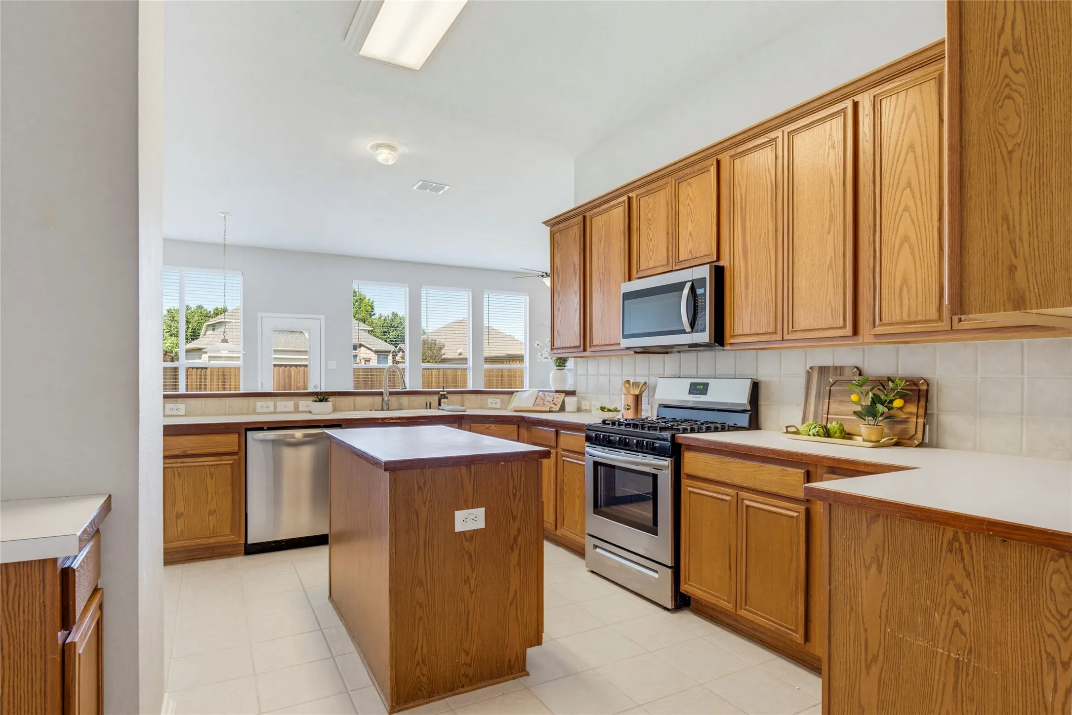 The kitchen features stainless steel appliances including a gas range and has plenty of cabinets for storage.