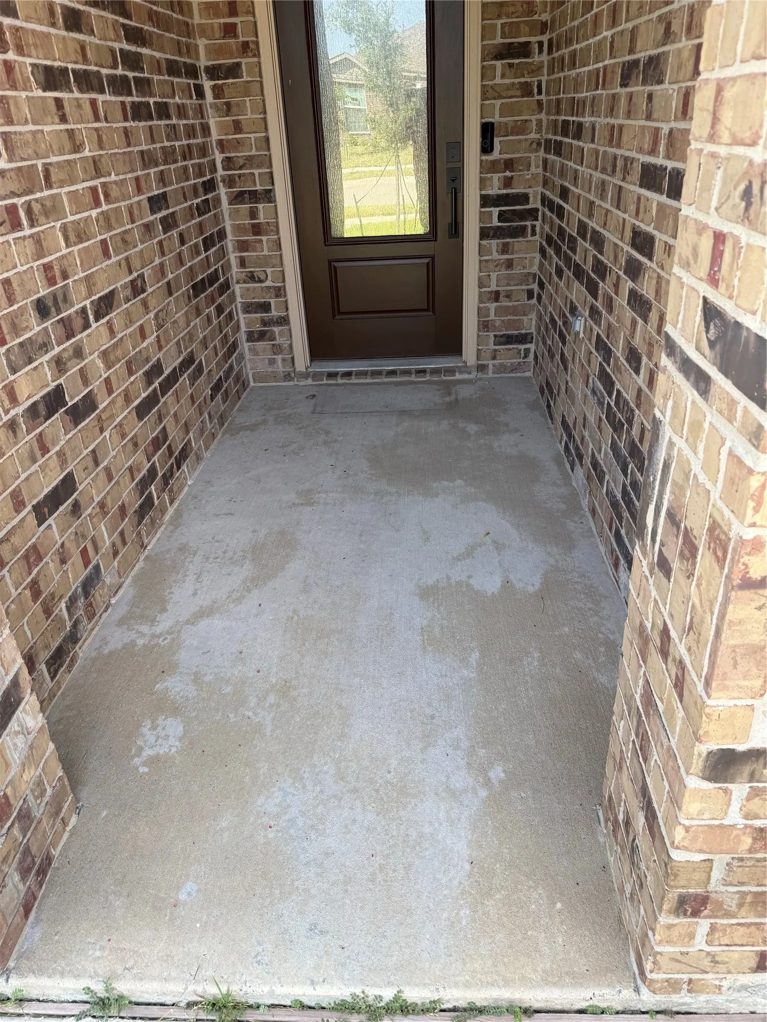 Brick exterior with a brown paneled entry door featuring a full-light glass insert