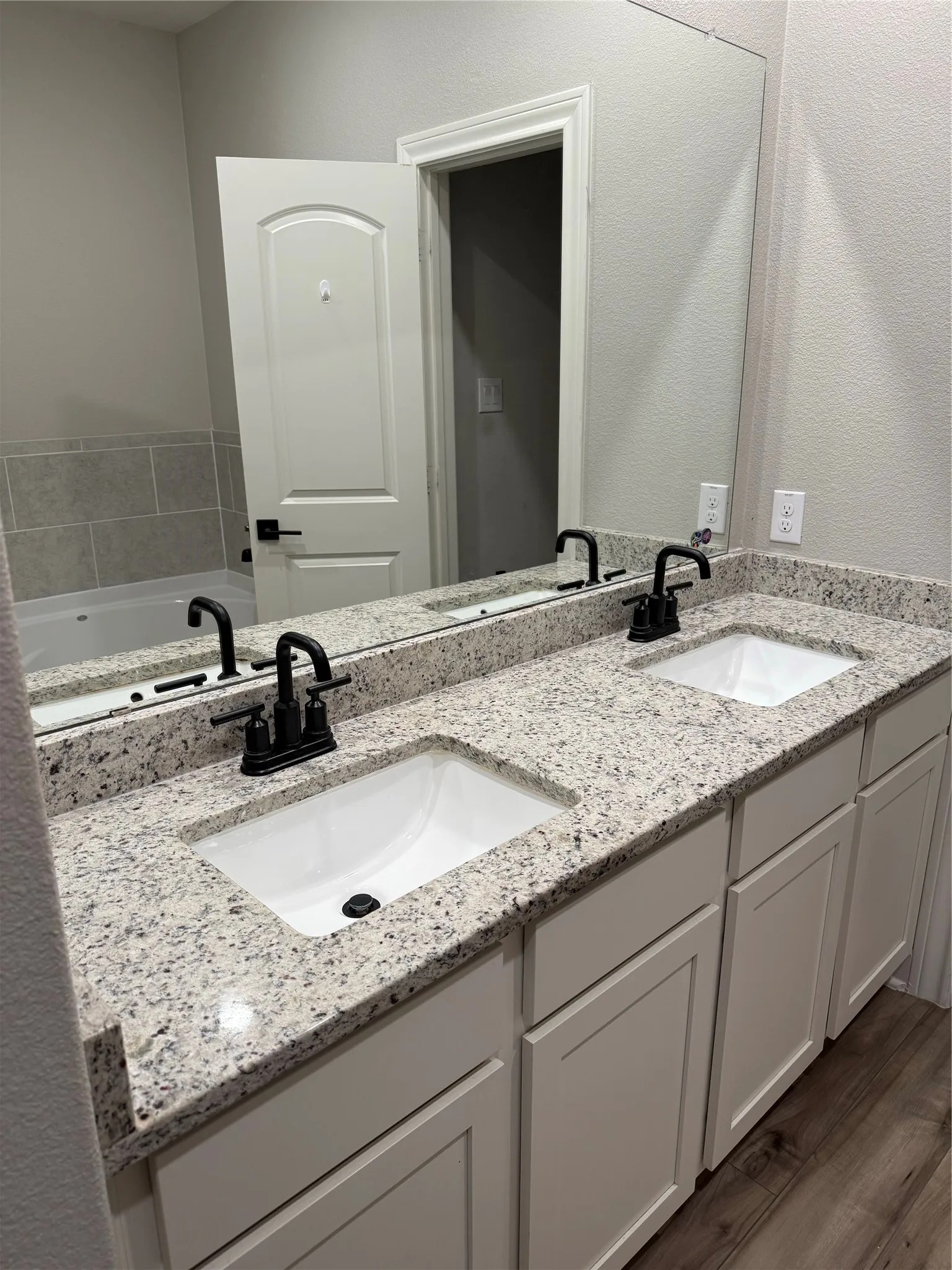 Dual vanity with granite-style countertop, undermount sinks, and matte black fixtures