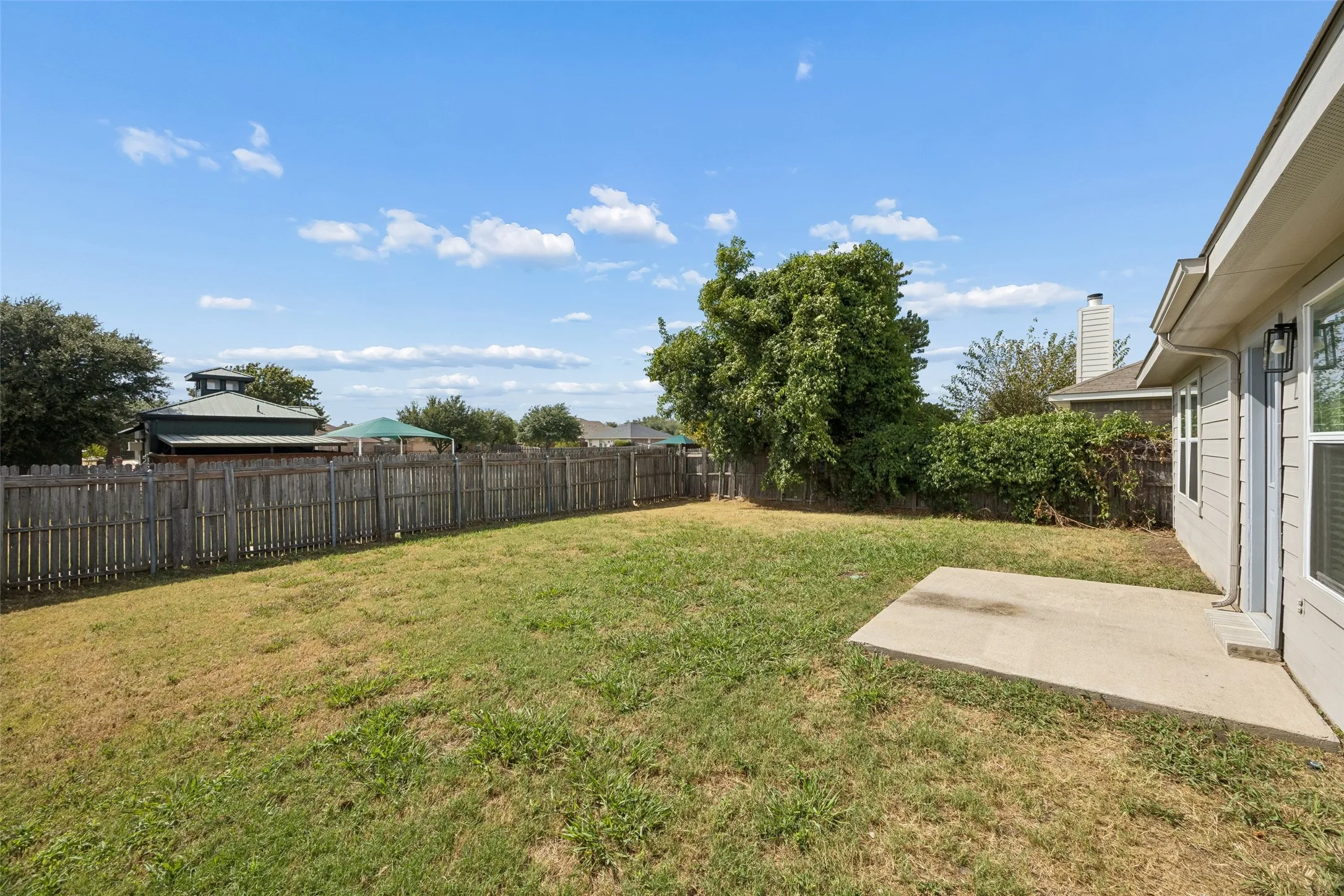 large yard.   Notice the roof to the pool just beyond the fence
