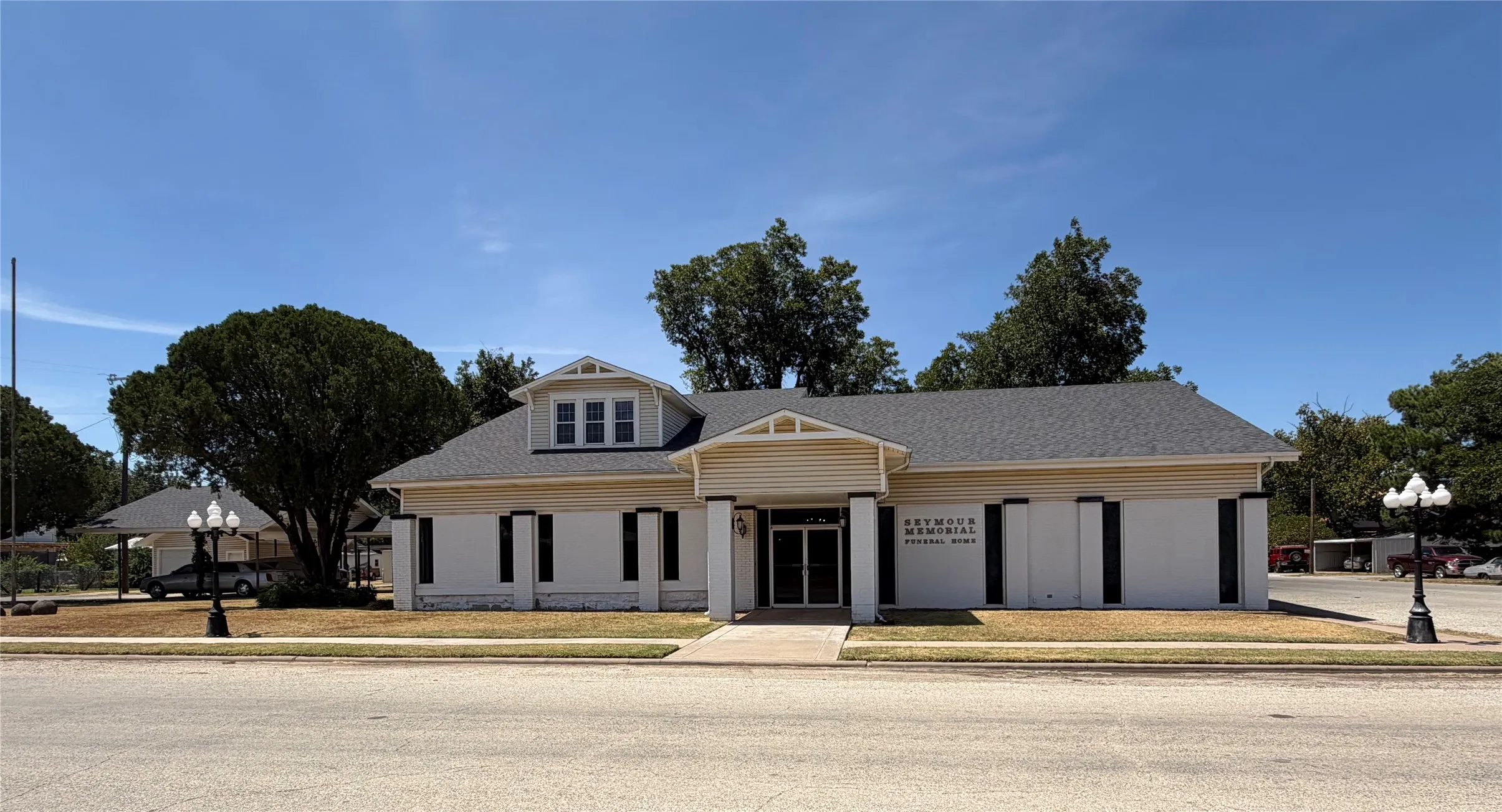 White siding exterior with dark shutters, gabled roofline, and dormer window