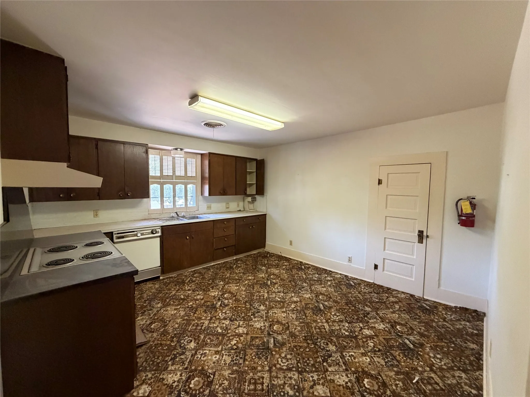 Kitchen featuring wood cabinetry, white countertops, built-in dishwasher, and a window above the sink