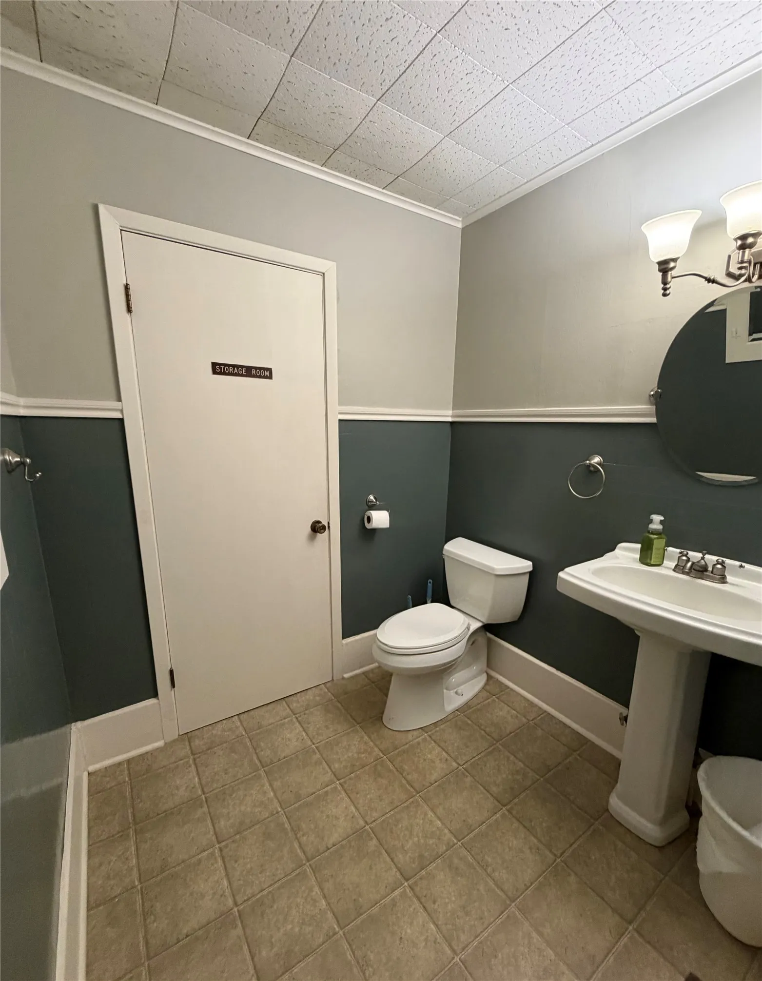 Pedestal sink, wall-mounted vanity lighting, and ceramic tile flooring