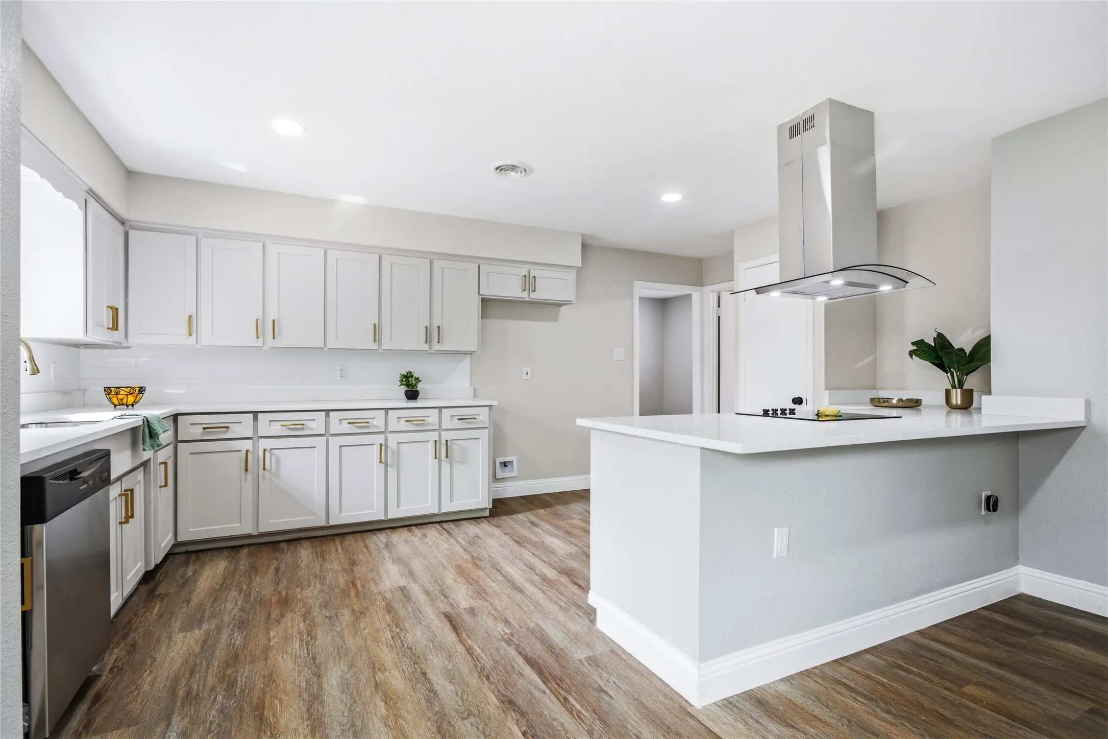 Renovated kitchen featuring white cabinetry, wood-finish flooring, recessed lighting, white countertops, and a modern range hood