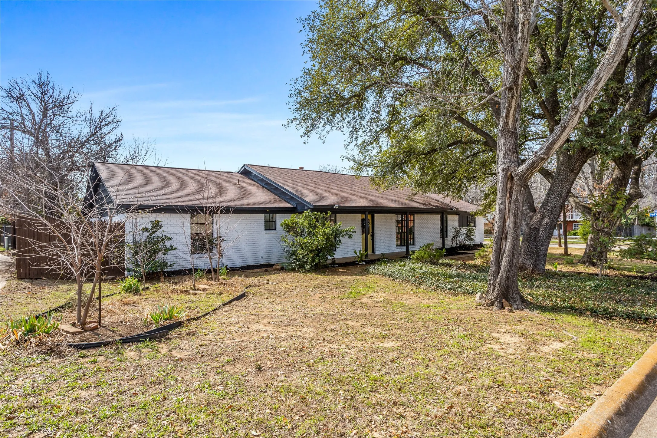 White brick exterior with a dark shingled roof, featuring mature trees and established​​‌​​​​‌​​‌‌​‌‌​​​‌‌​‌​‌​‌​​​‌​​ landscaping