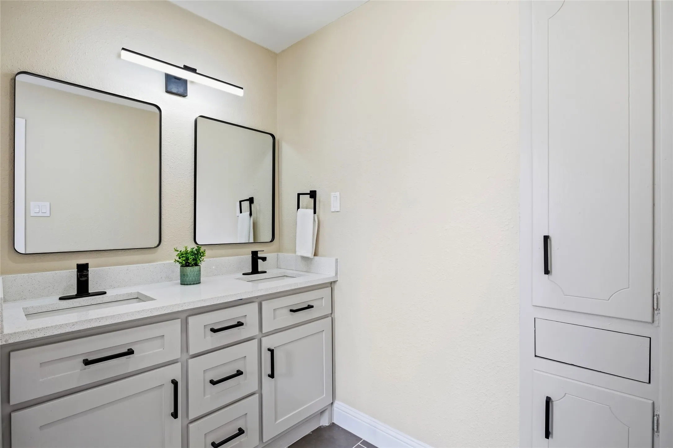 Dual vanity with integrated sinks, light-toned countertop, matte black fixtures, and framed mirrors