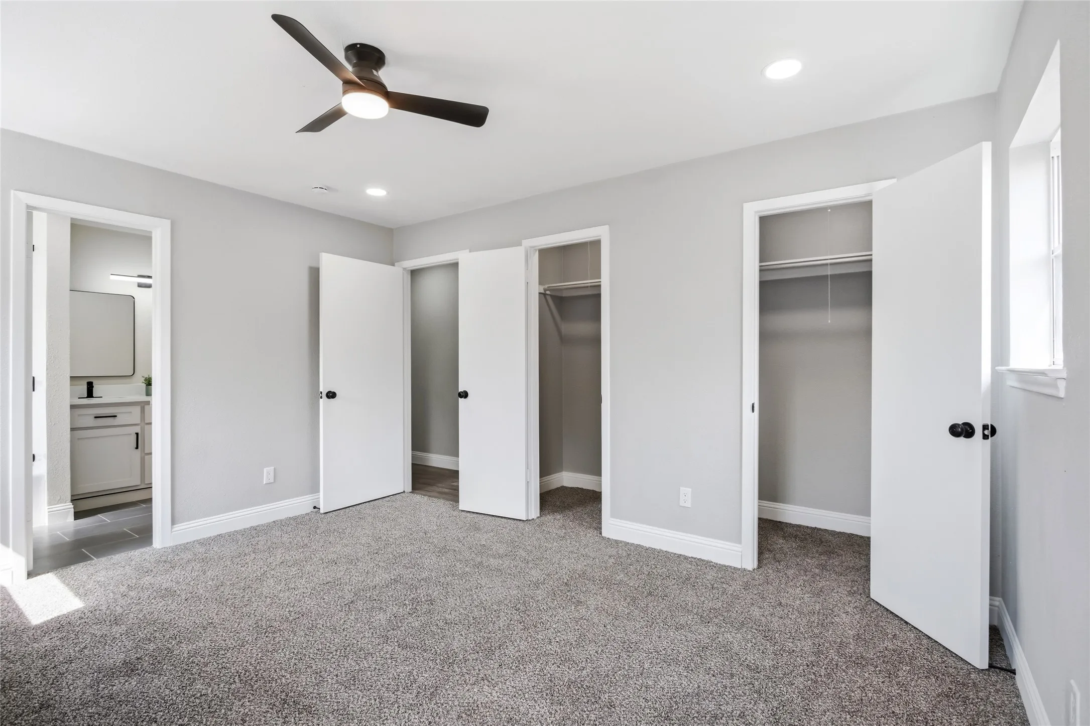 Spacious room featuring plush gray carpeting, a modern ceiling fan with integrated lighting, recessed lighting, and ample closet space with bi-fold doors