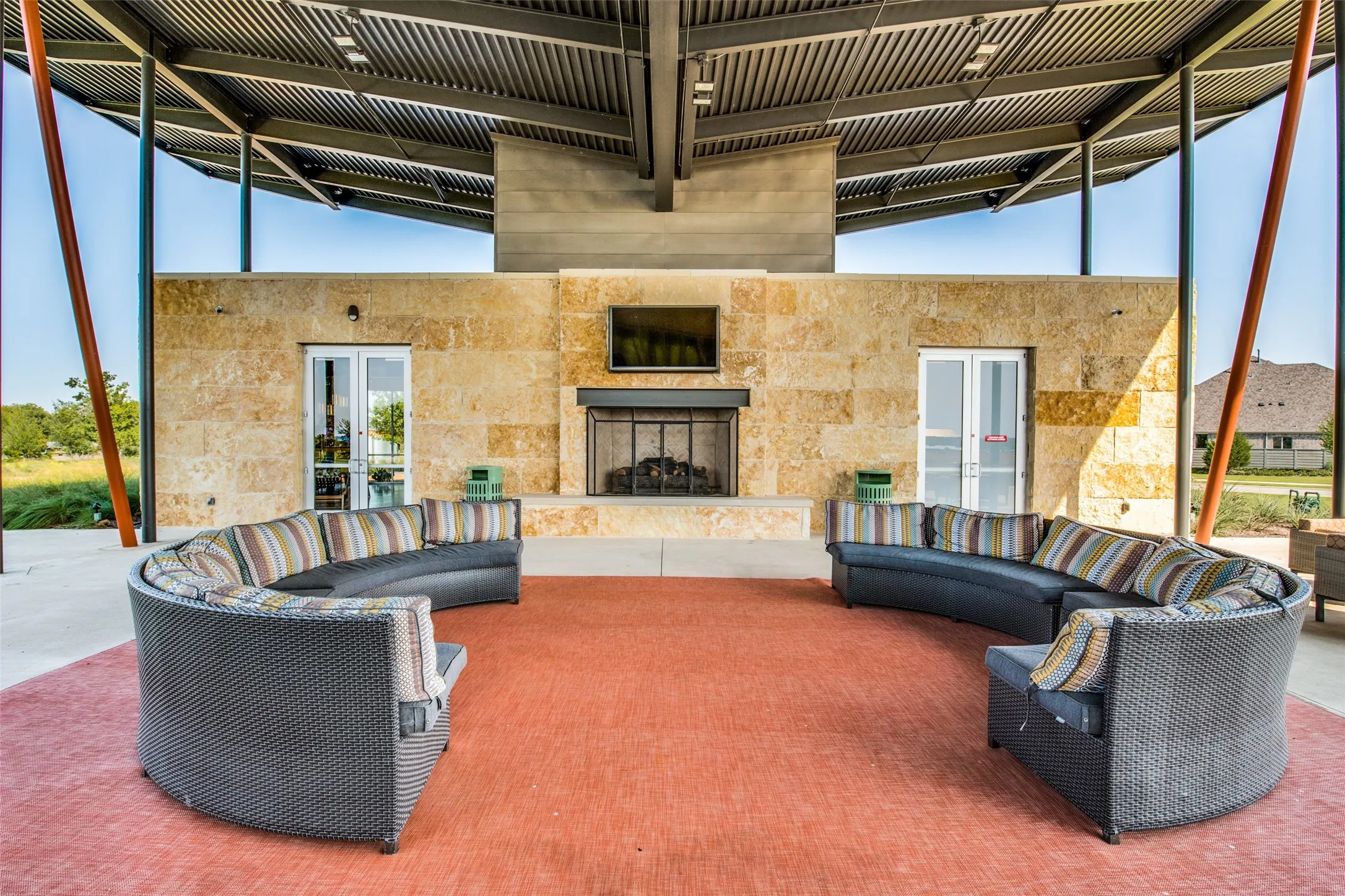 Outdoor covered patio featuring a stone-clad fireplace and a metal roof