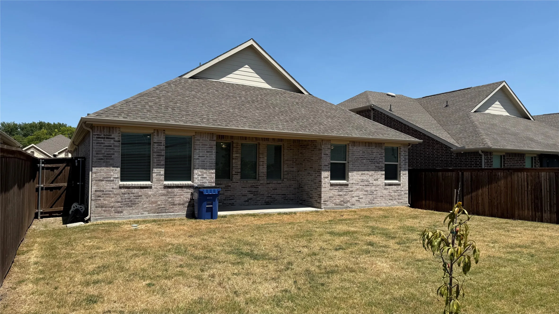 Private backyard with a covered patio, brick exterior, and wood fencing