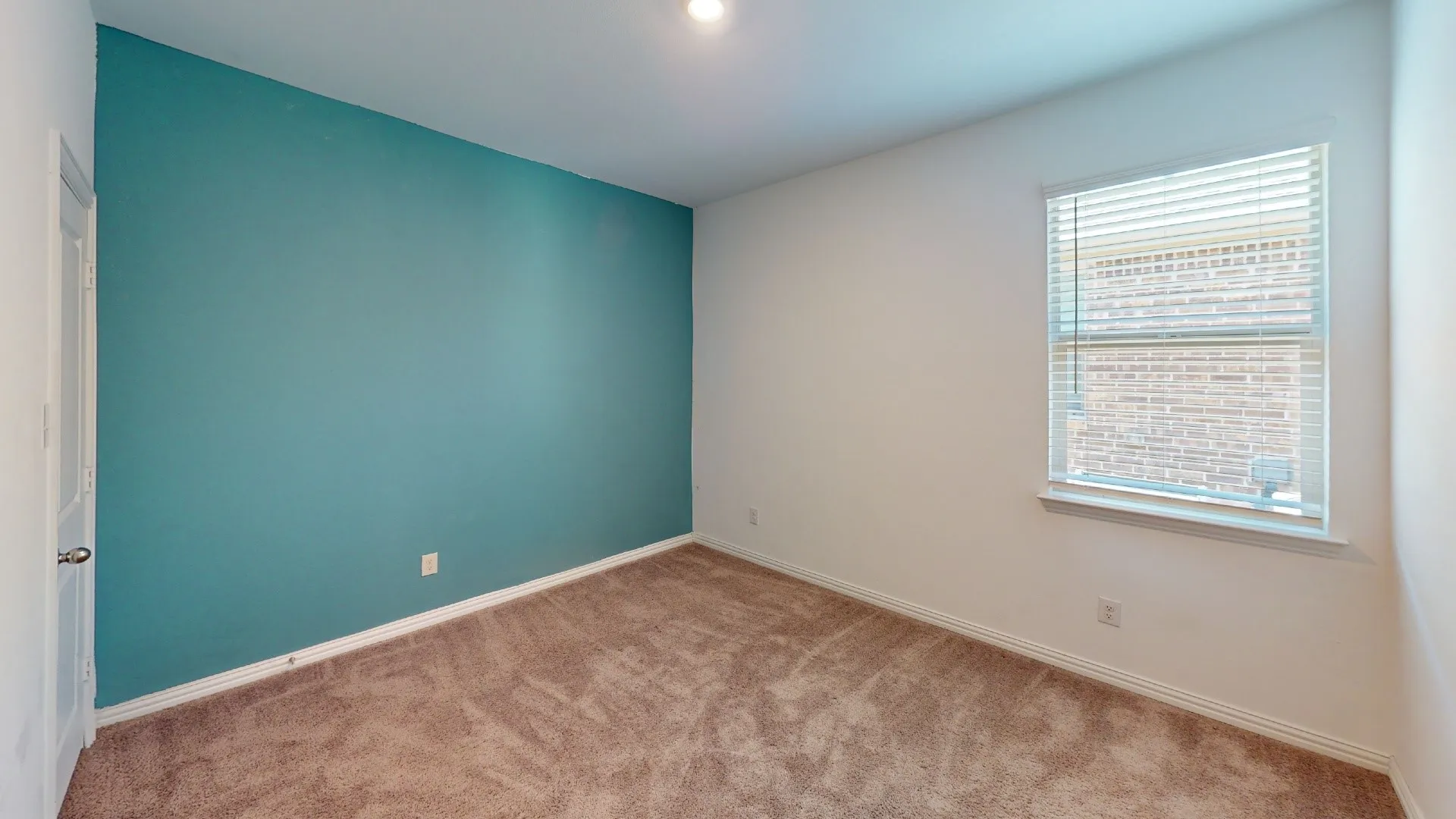 Carpeted room with a teal accent wall, white painted walls, and a window with blinds