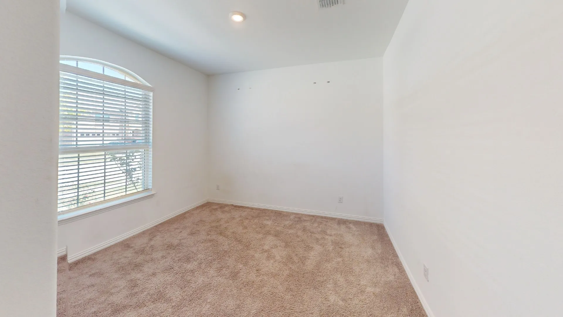 Arched window with blinds, recessed lighting, and carpeted flooring