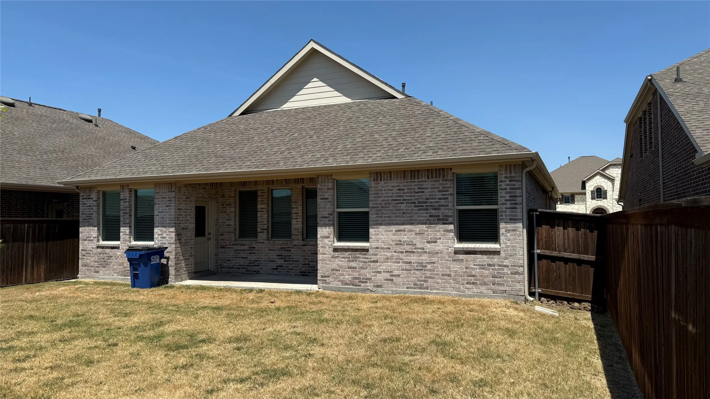 Brick exterior with multiple windows, covered patio, and fenced yard